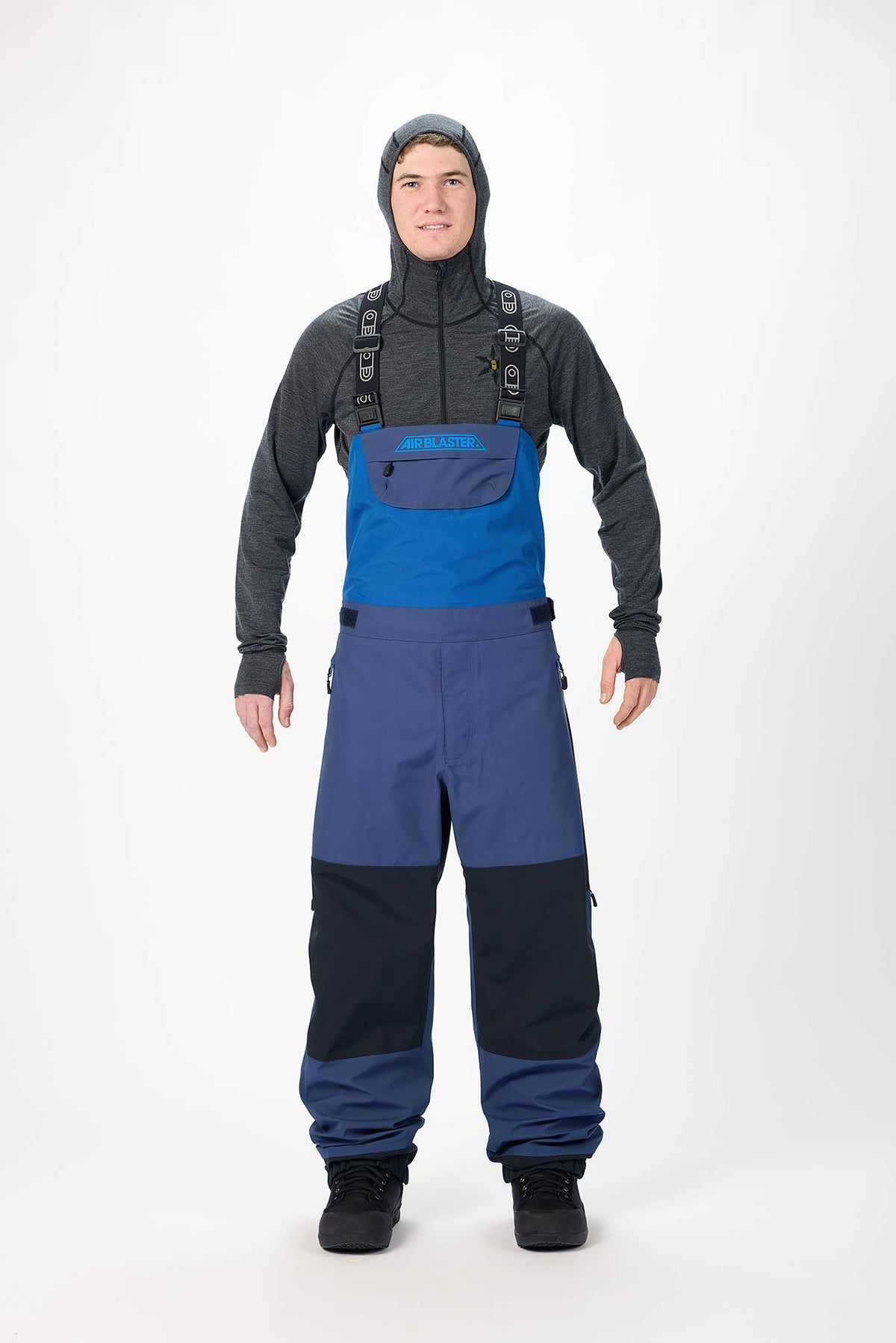 Person wearing a black jacket and blue snow pants on a white background