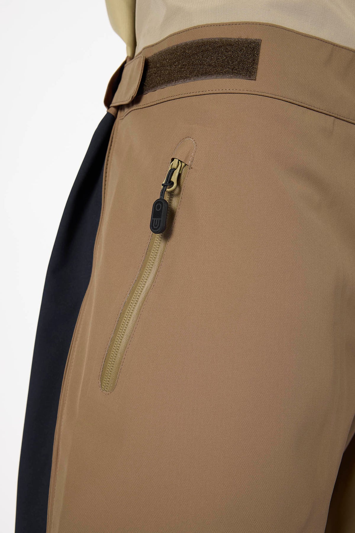 Close-up of beige pants with a zipper pocket on a white background