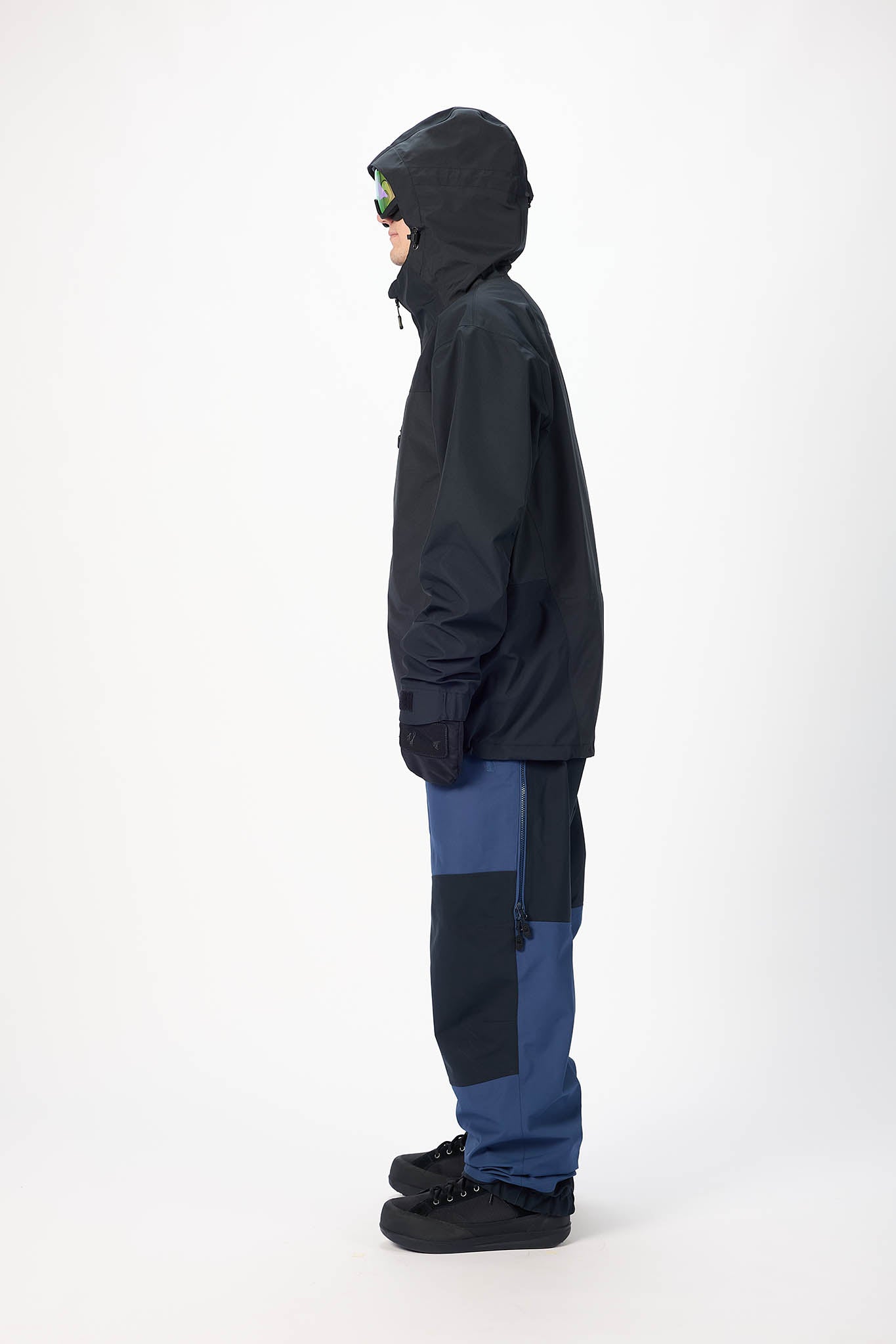 Person wearing a black and blue snowsuit on a white background