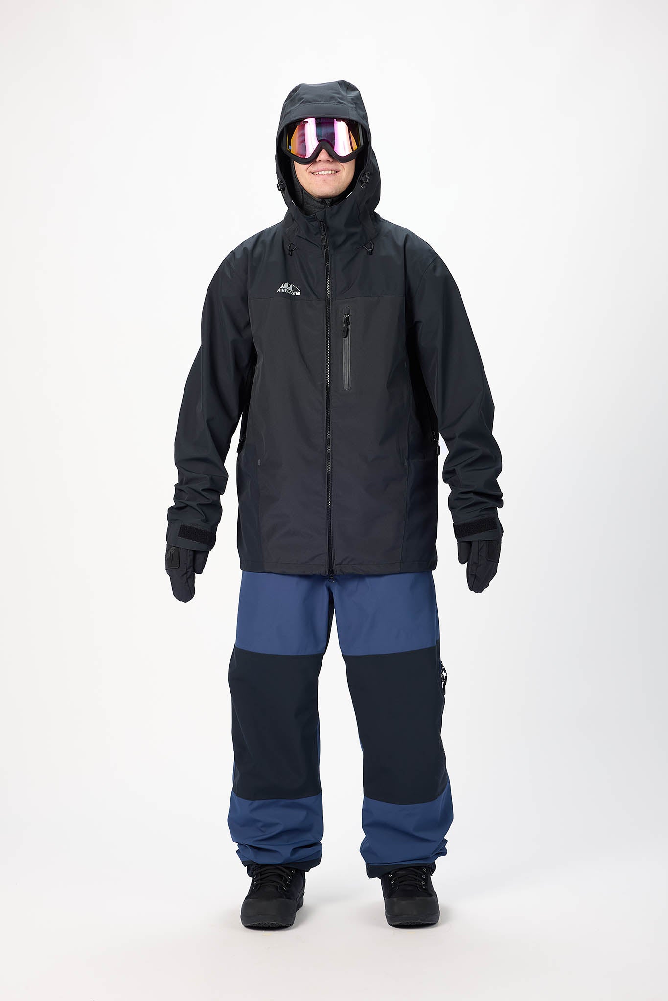 Person wearing a black and blue snowsuit with goggles on a white background