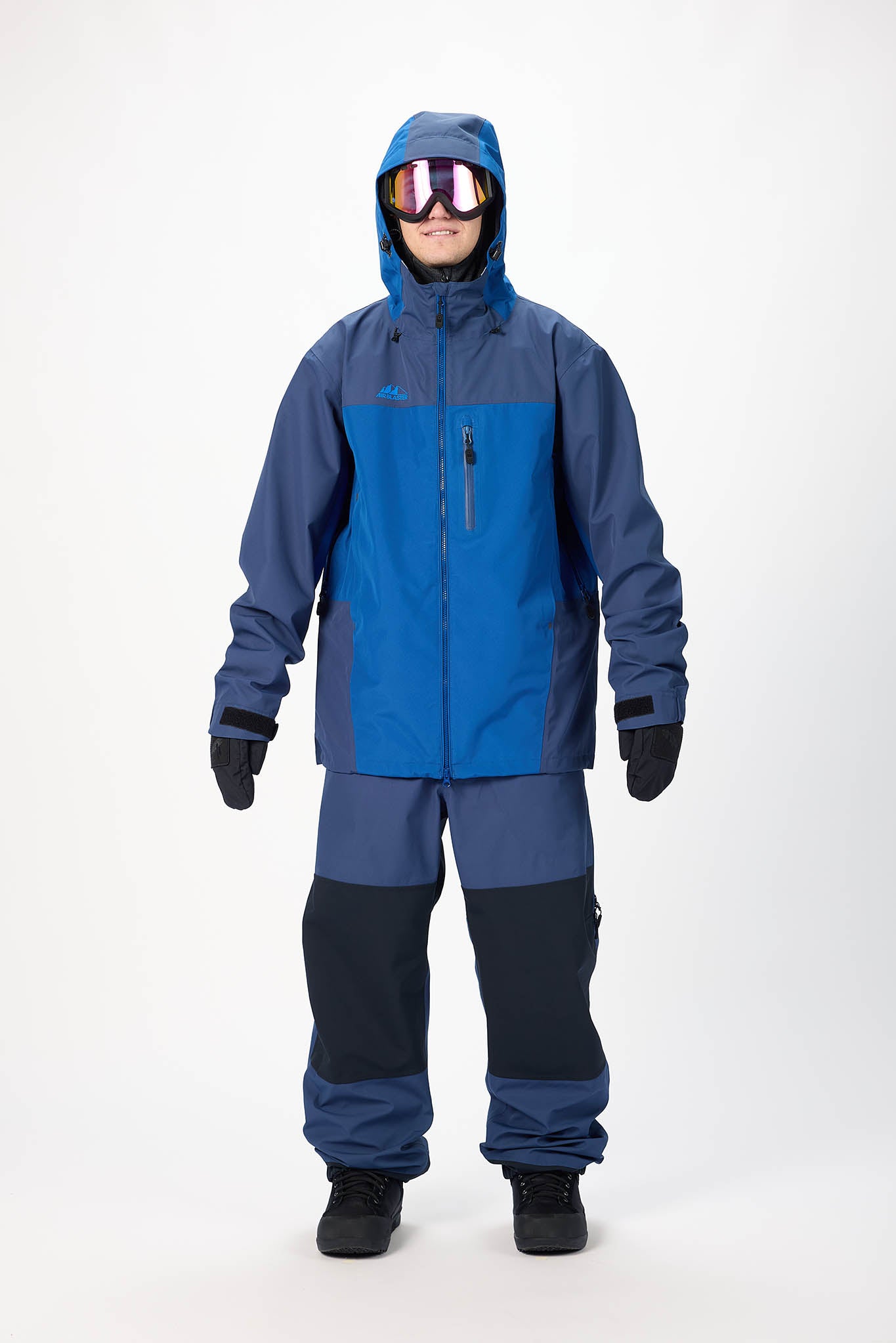 Person wearing a blue and gray snowsuit with goggles on a white background