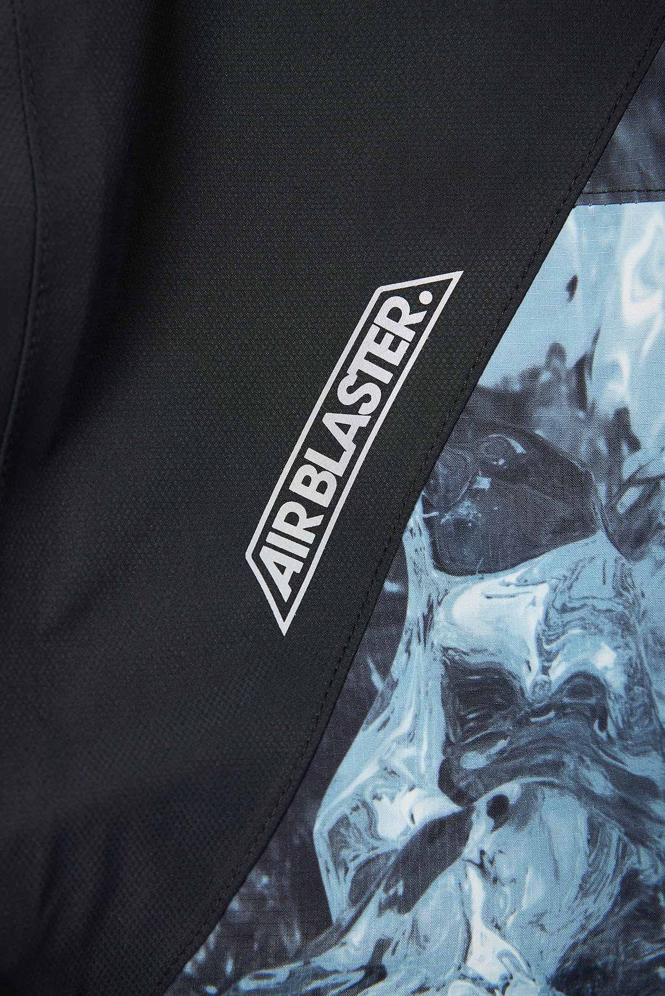 Close-up of a black jacket with 'Airblaster' logo and abstract design.