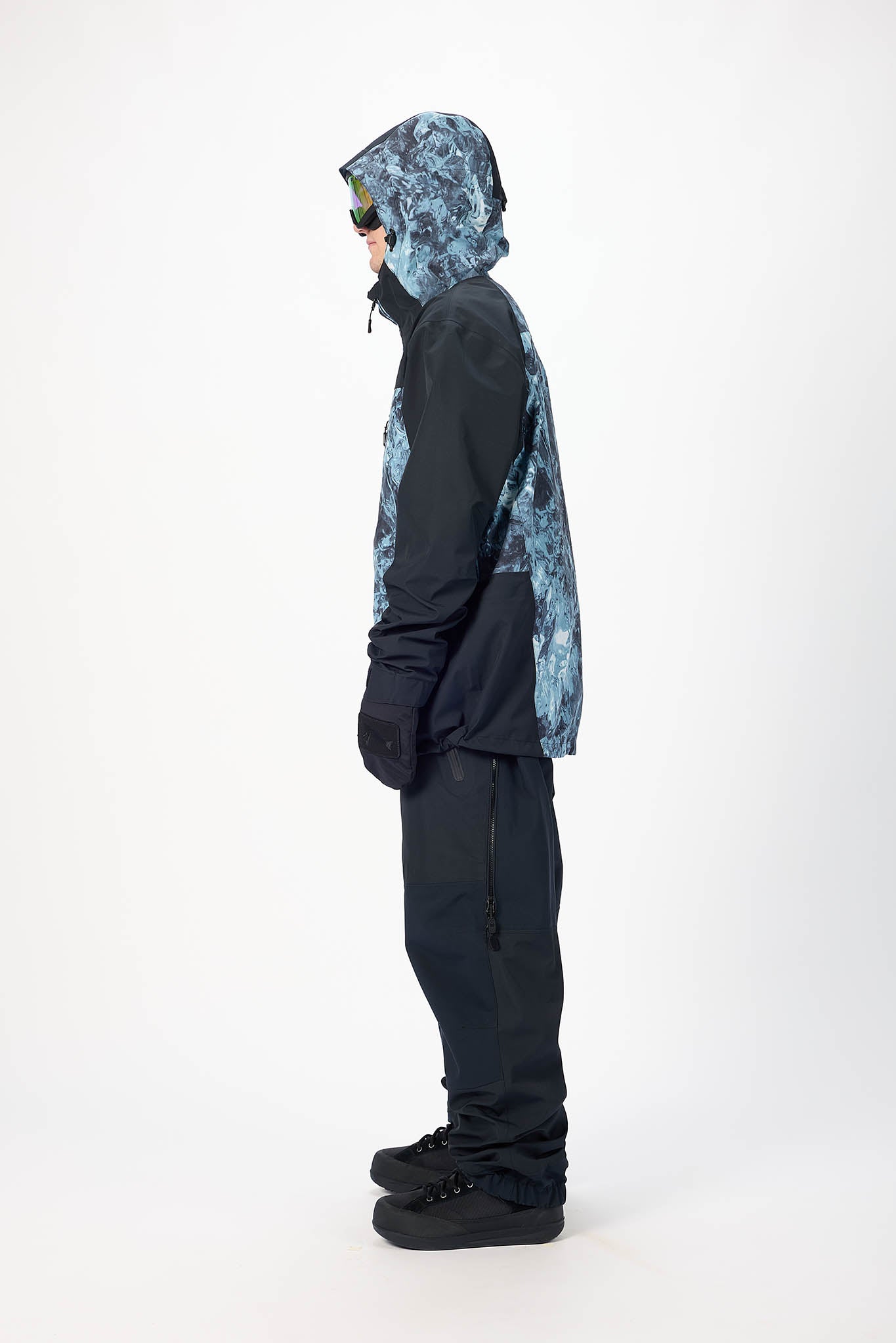 Person wearing a black and blue patterned snowsuit on a white background