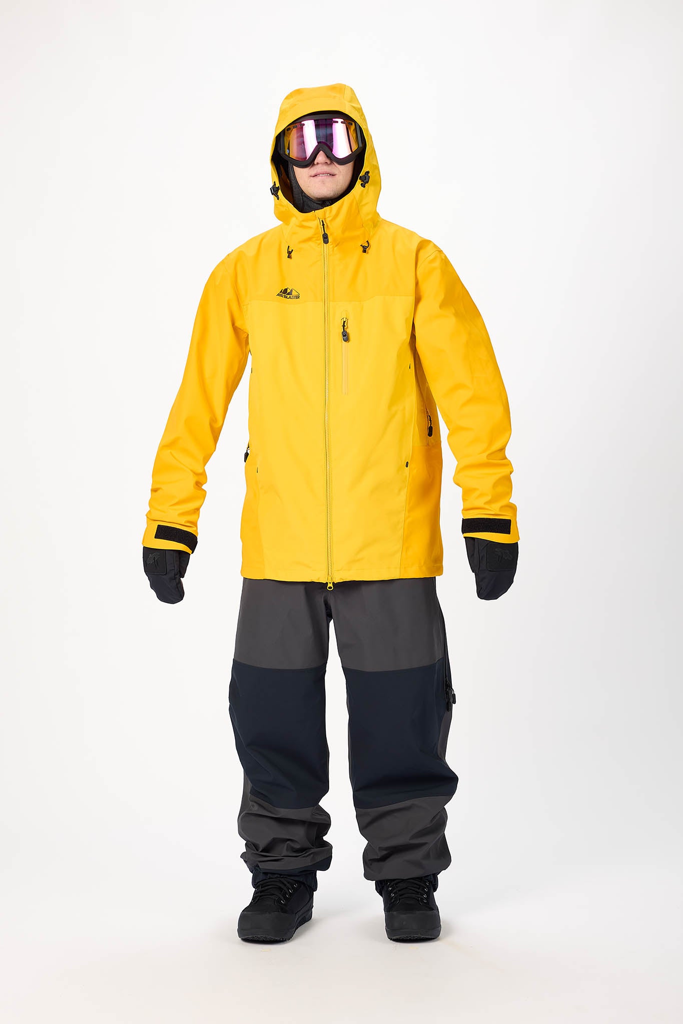 Person wearing a yellow snow jacket and black pants on a white background