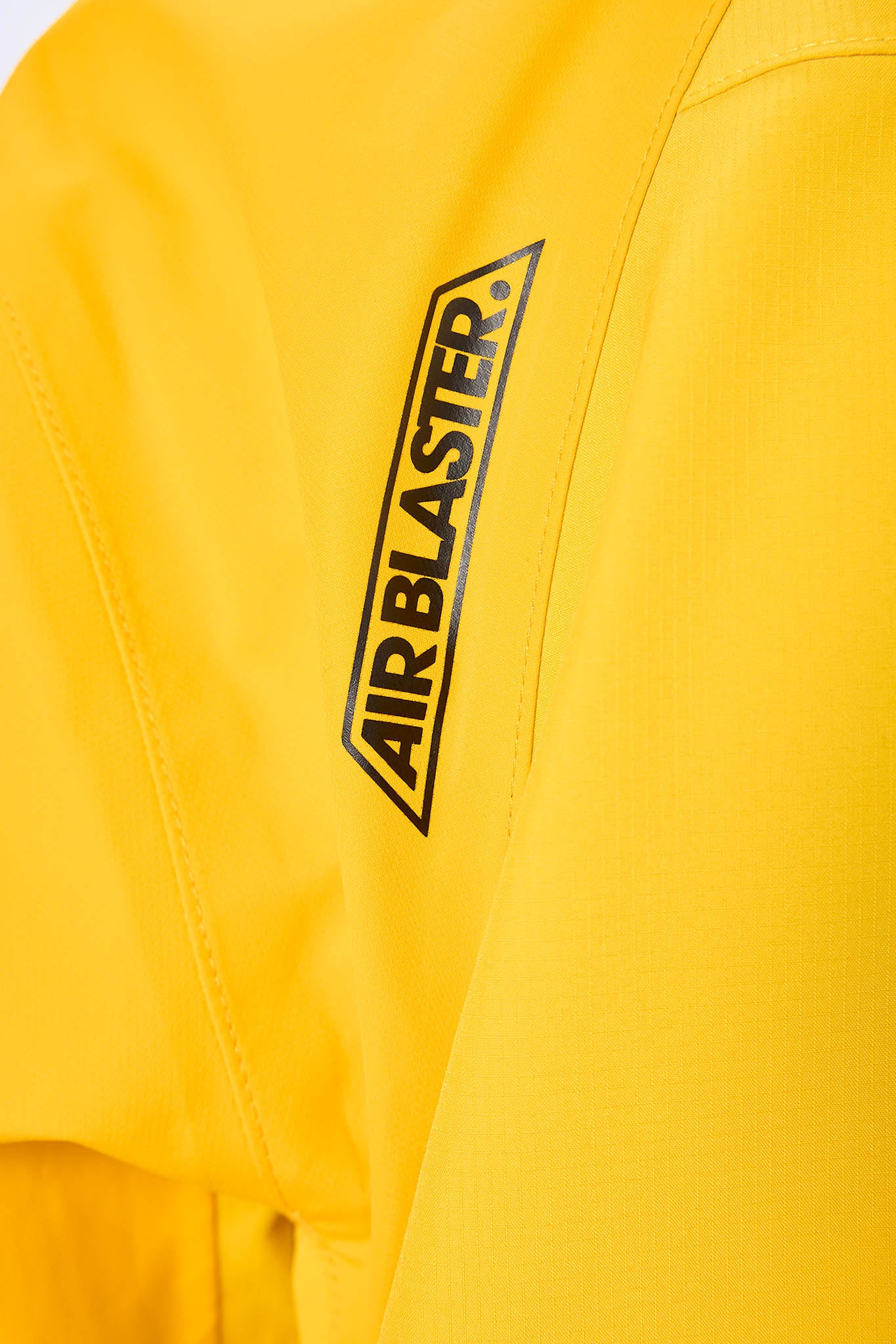 Close-up of a yellow jacket with 'AIRBLASTER' logo on a white background
