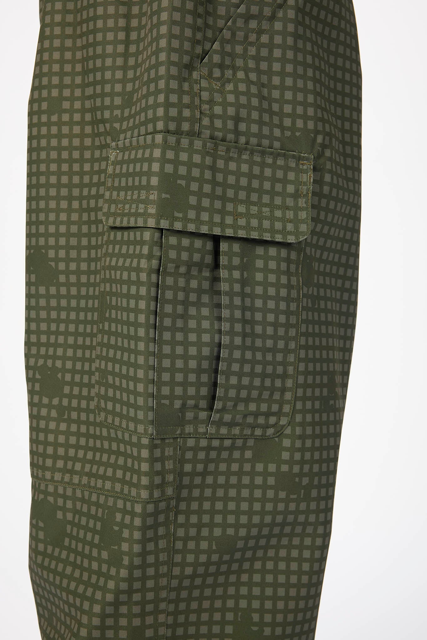 Close-up of olive green cargo pants featuring a small grid pattern and a flap cargo pocket, shown against a plain white background.