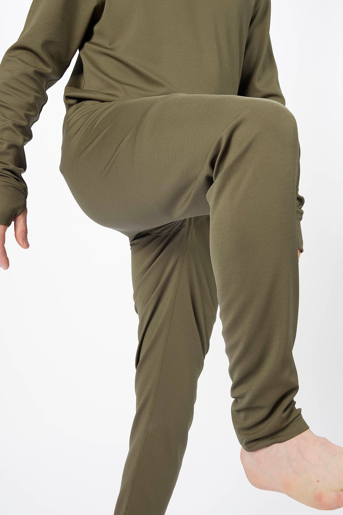 A person wearing an olive green ribbed knit pajama set, featuring a long-sleeve top and matching pants, shown from the chest down against a plain white background.