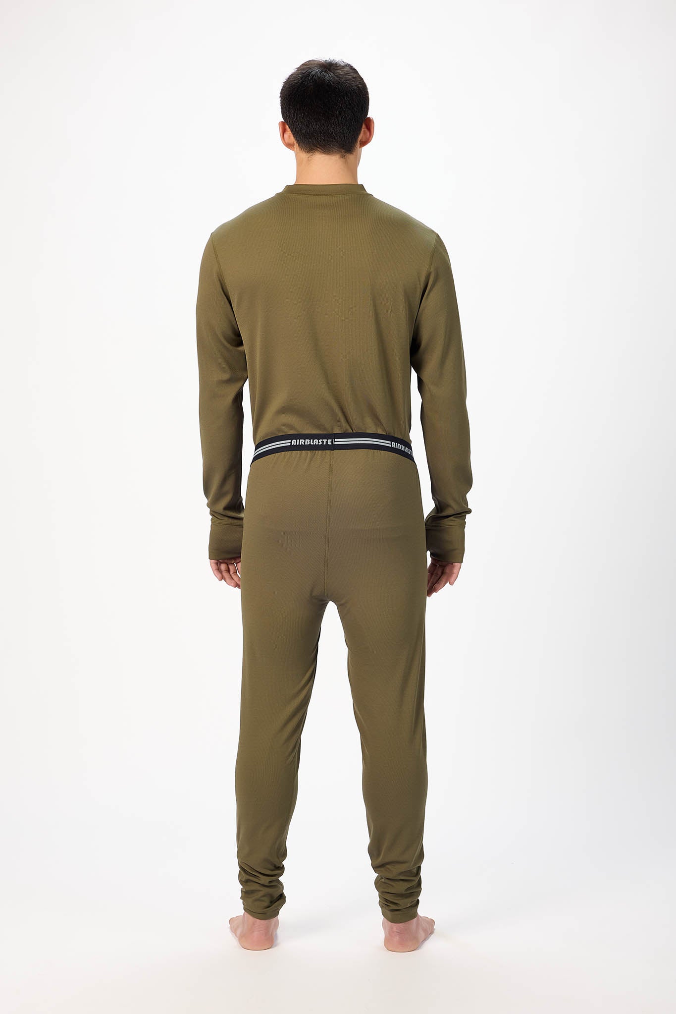 A man wearing a olive patterned long-sleeve base layer set, standing against a plain white studio background view from behind