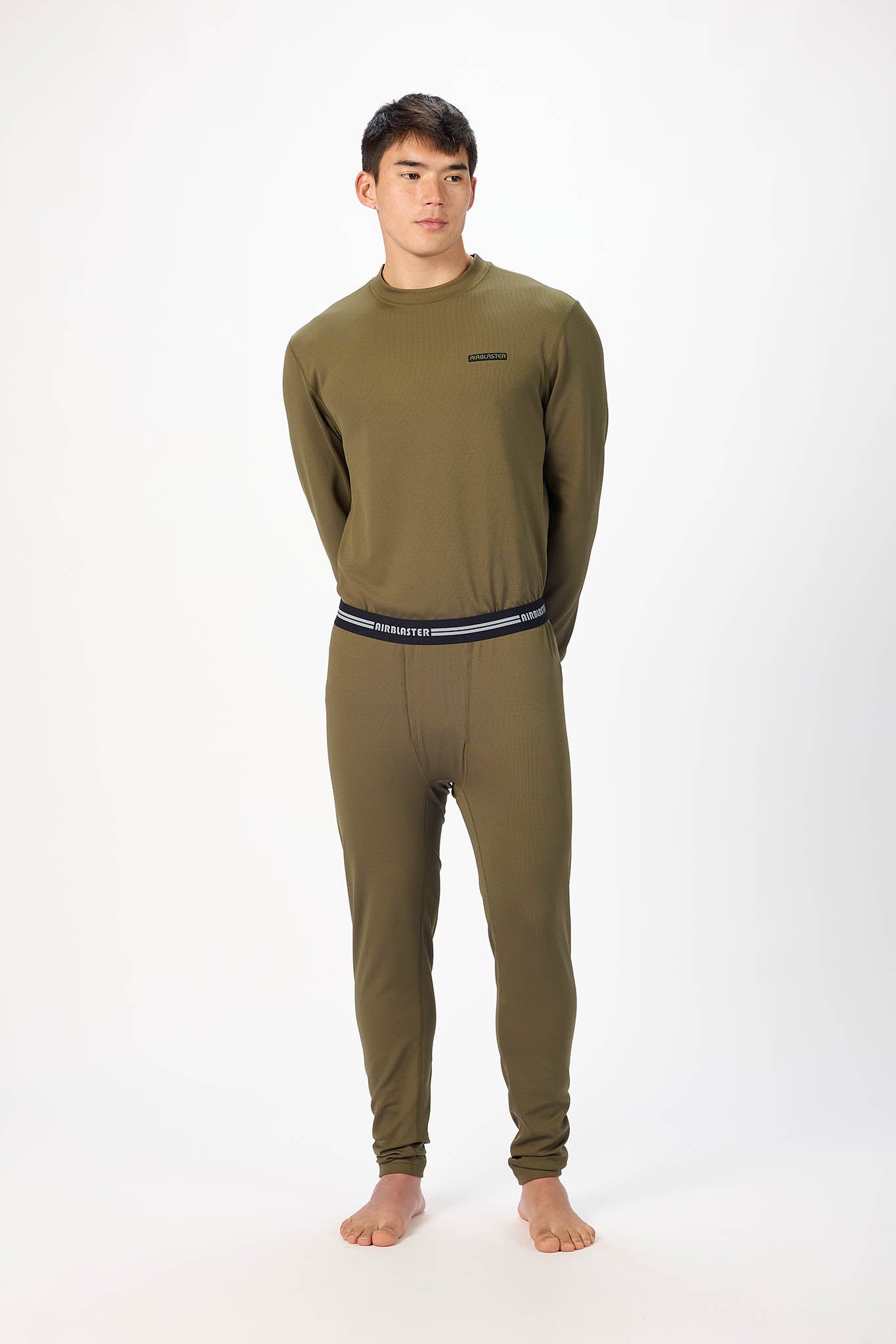 A man wearing a olive patterned long-sleeve base layer set, standing against a plain white studio background.