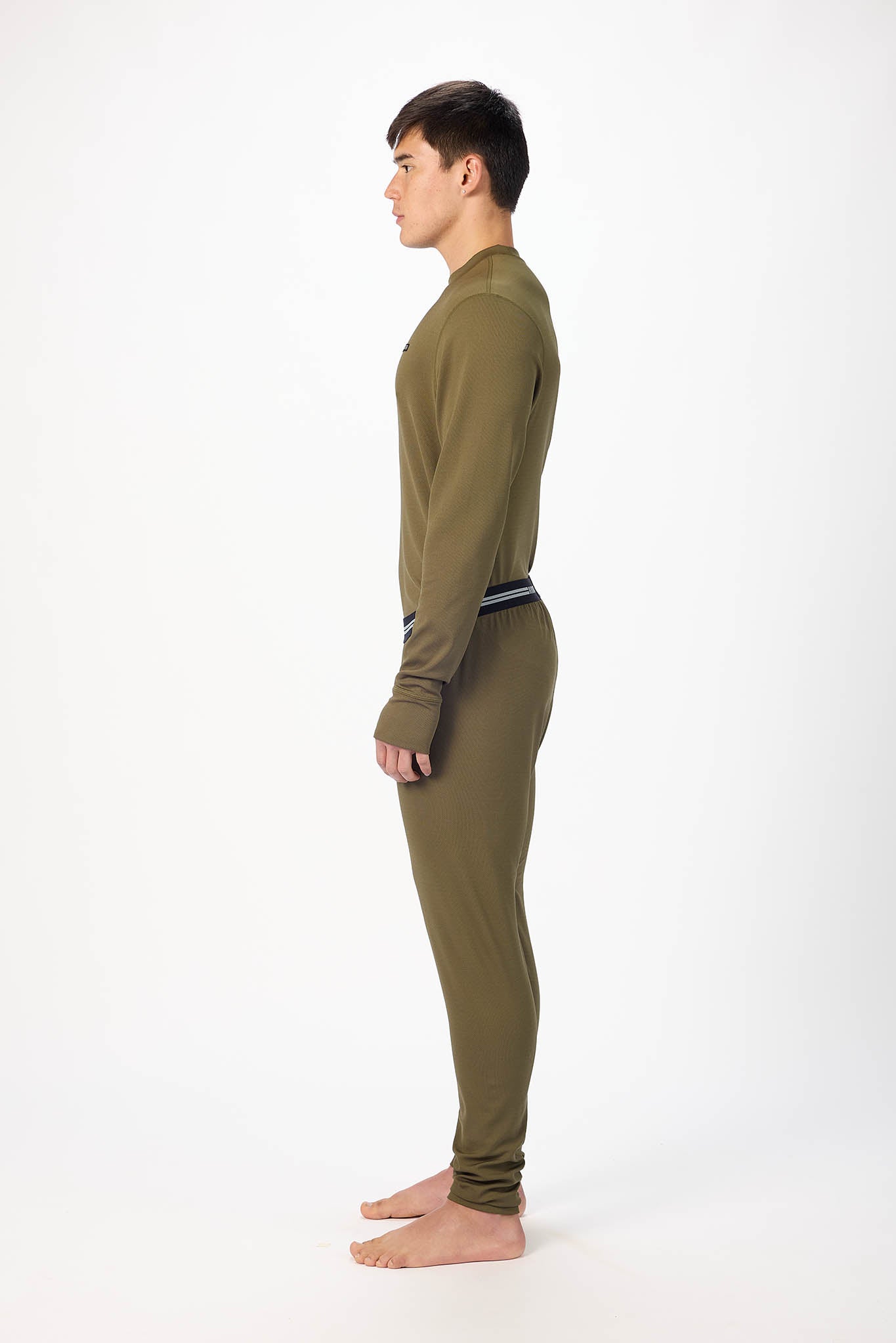 A man wearing a olive patterned long-sleeve base layer set, standing against a plain white studio background.