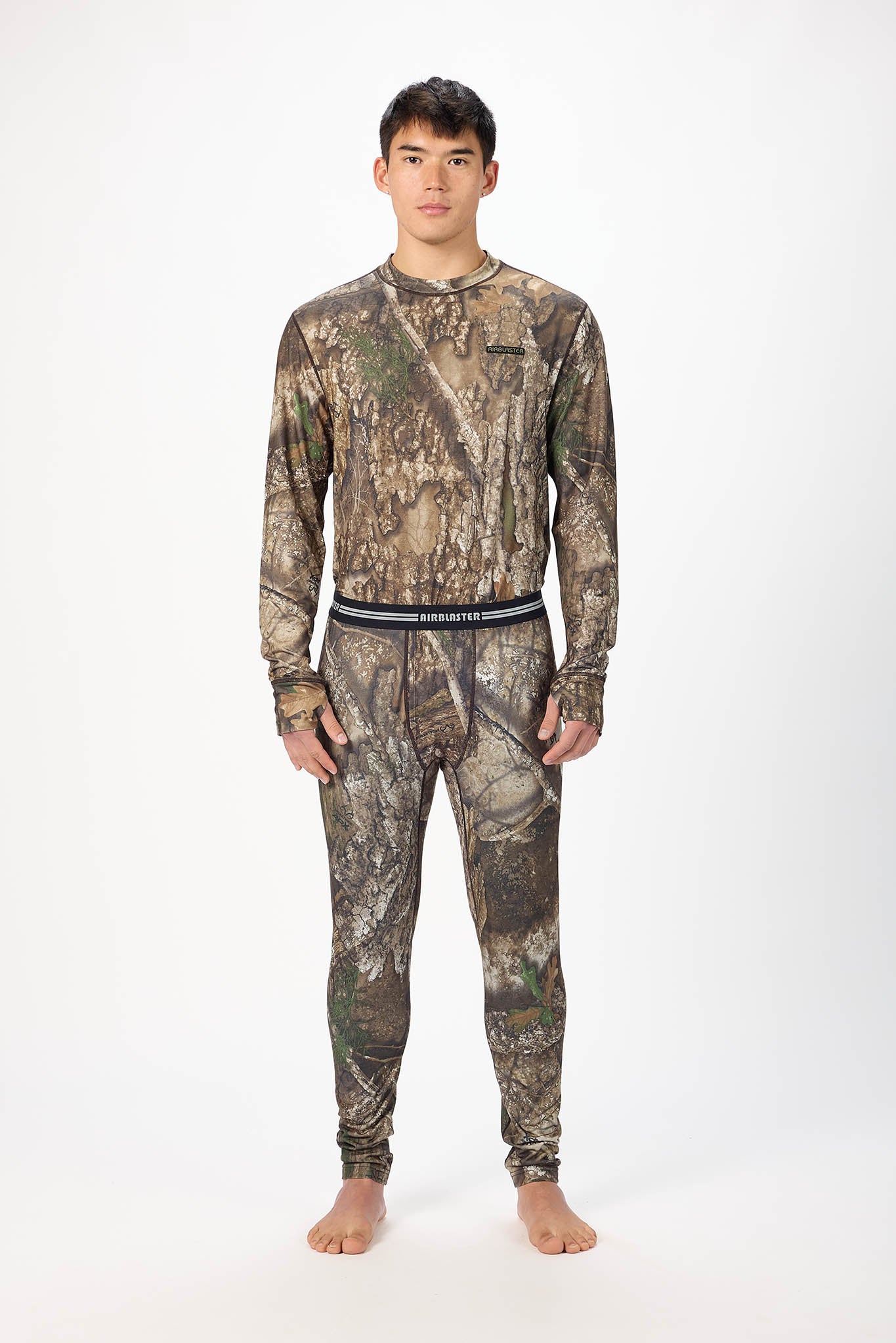 A man modeling a matching camouflage long-sleeve shirt and jogger pants set against a plain white studio background.