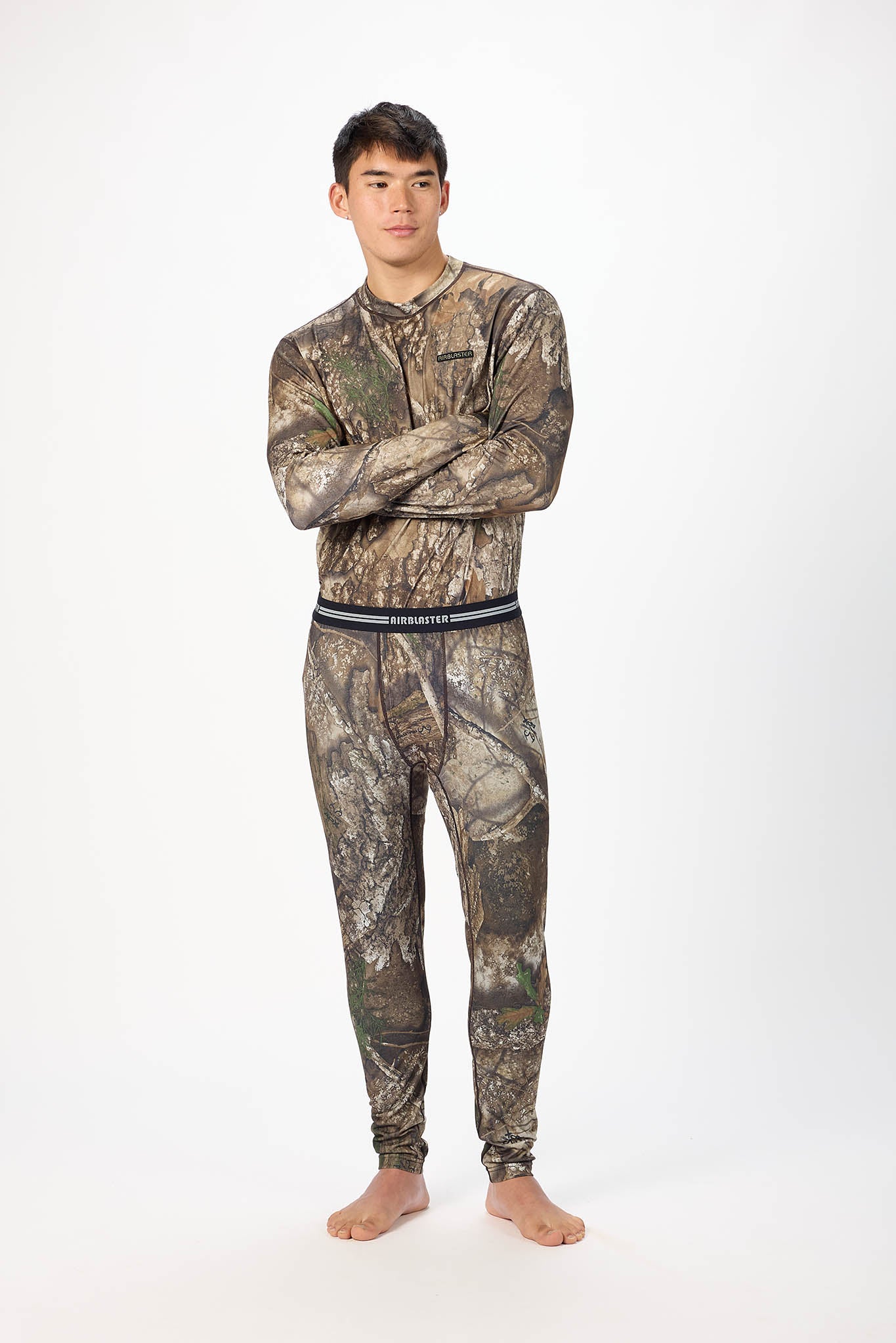 A man modeling a matching camouflage long-sleeve shirt and jogger pants set against a plain white studio background.