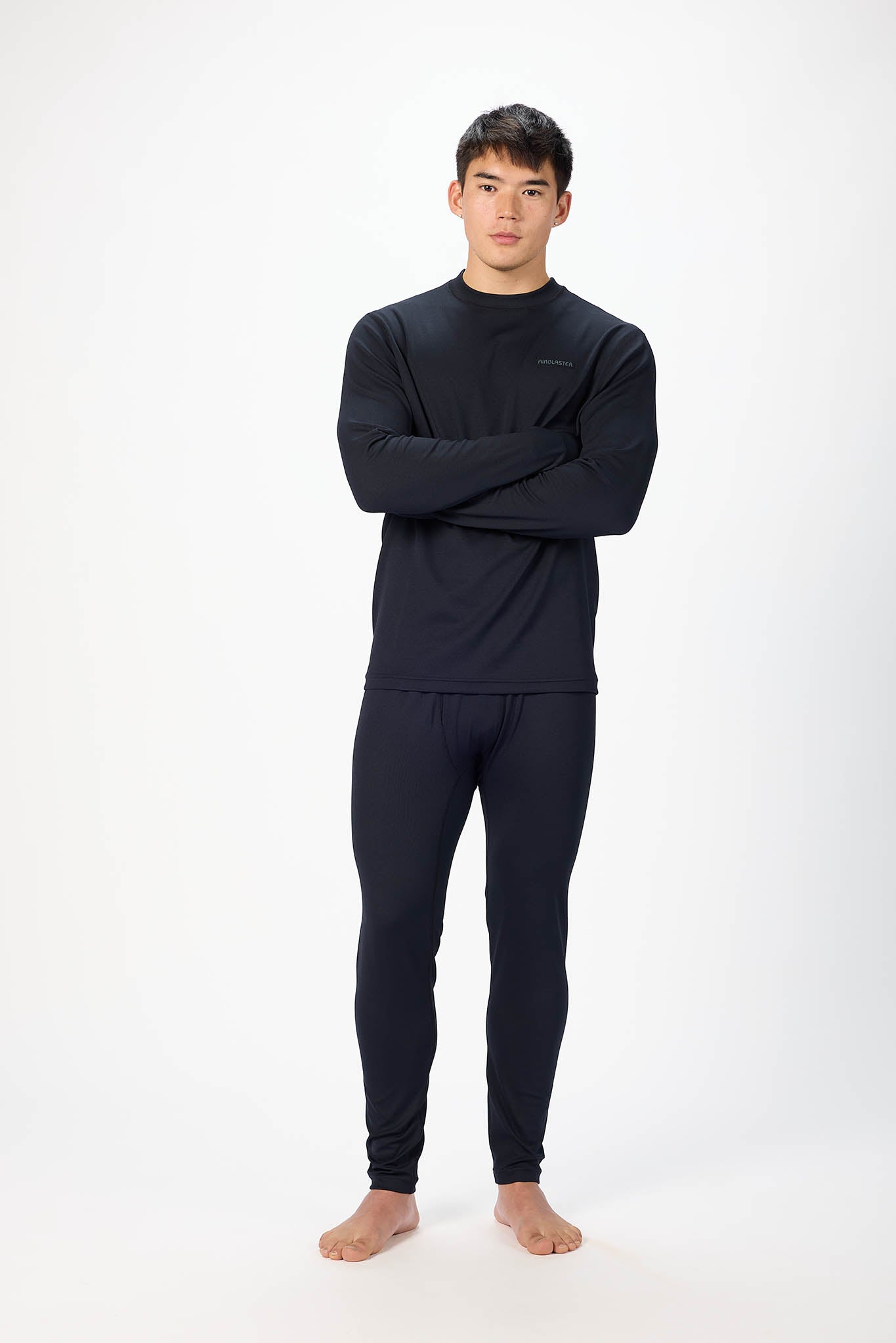 A man modeling a dark navy blue long-sleeve crewneck shirt and matching dark navy blue pants against a plain white studio background.