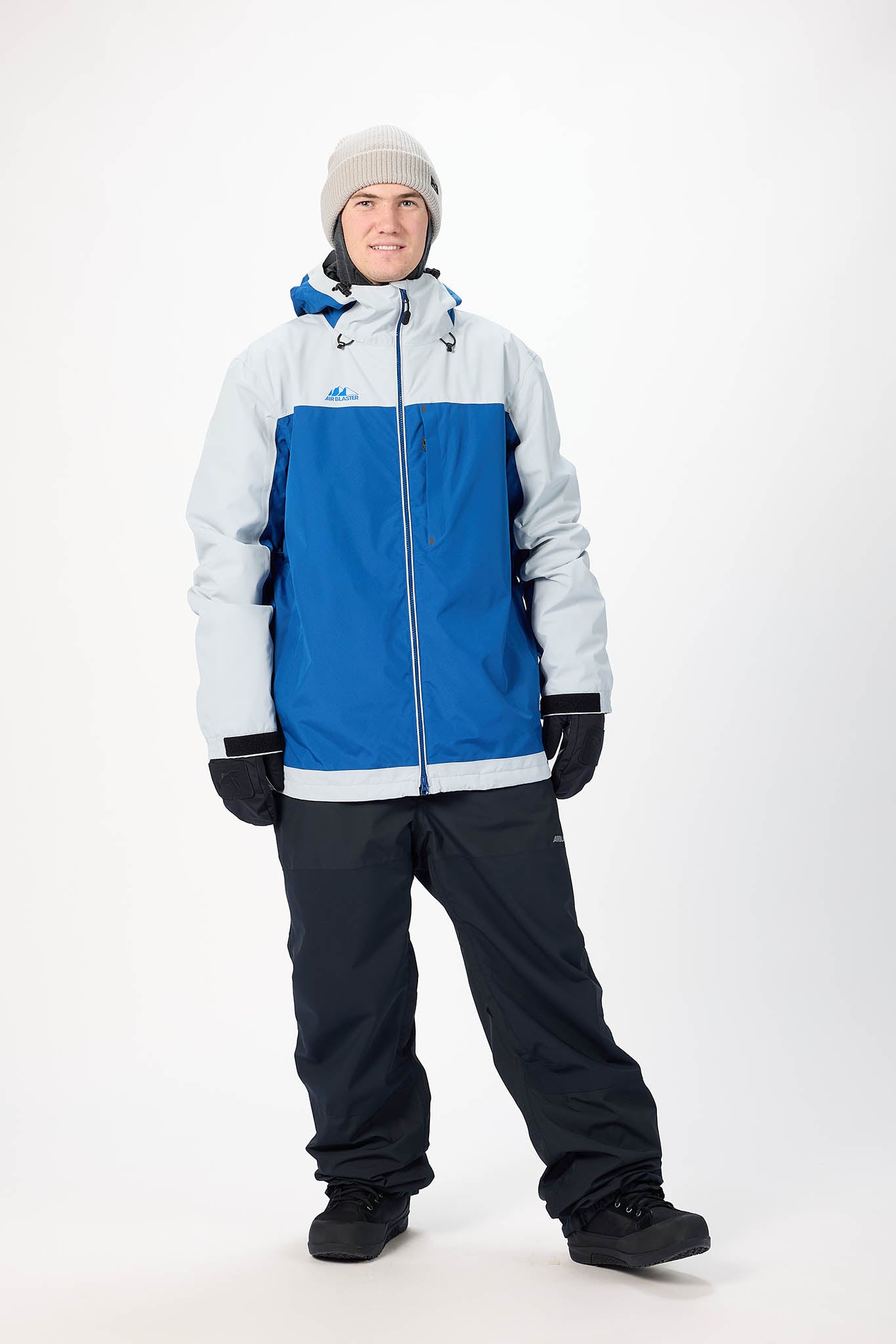Person wearing a blue and white snow jacket with black pants on a white background