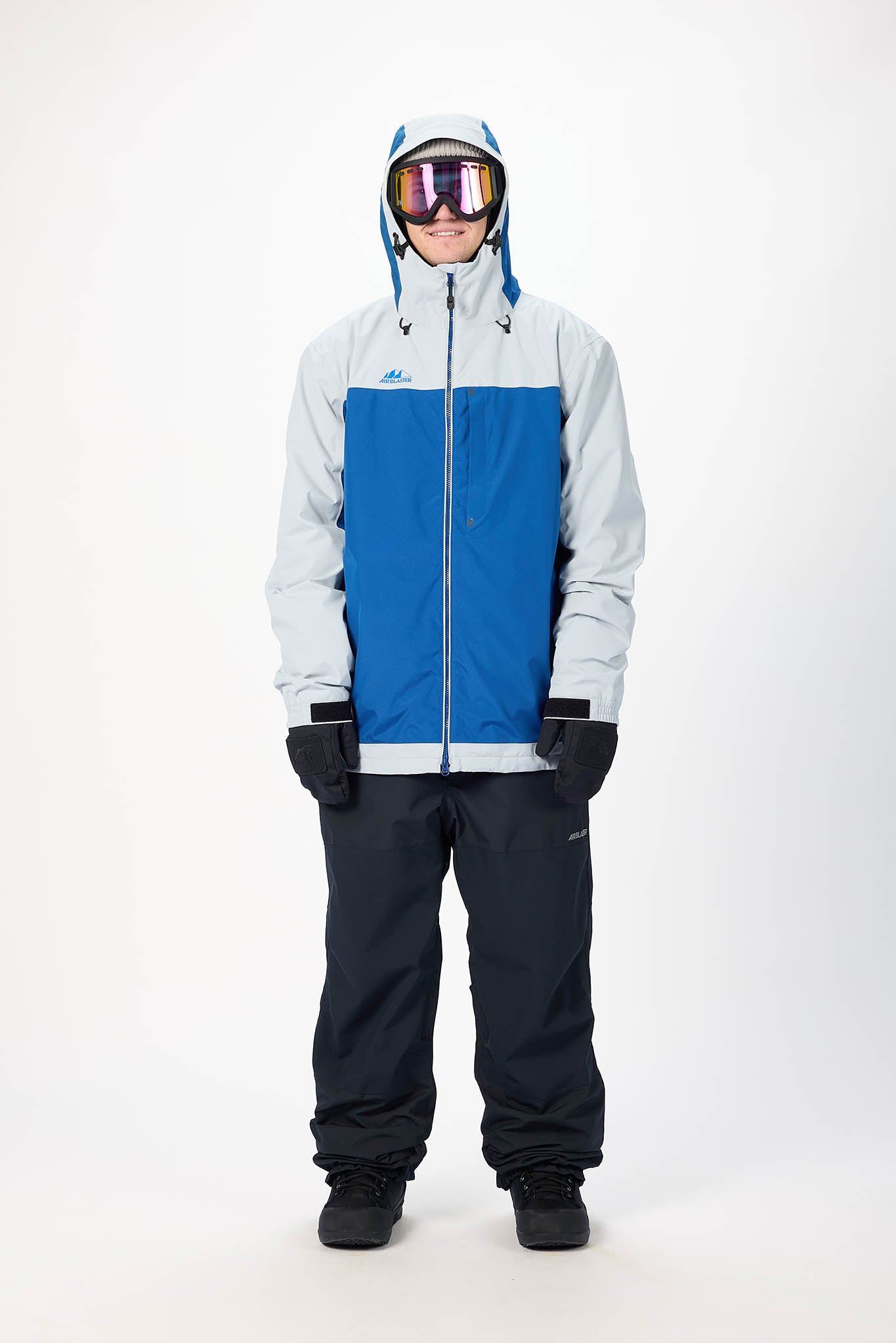 Person wearing a blue and gray snowsuit with goggles on a white background