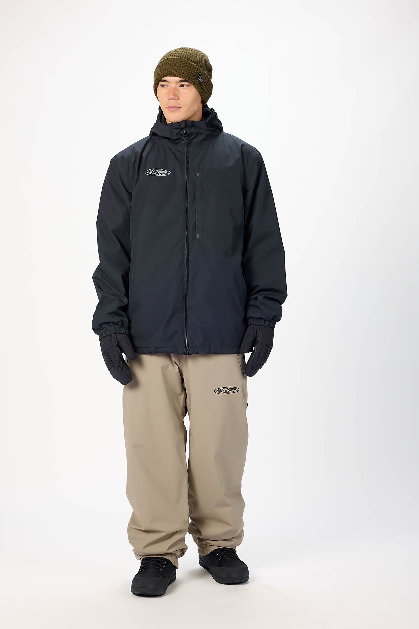 Person wearing a black jacket, beige pants, and a green beanie on a white background