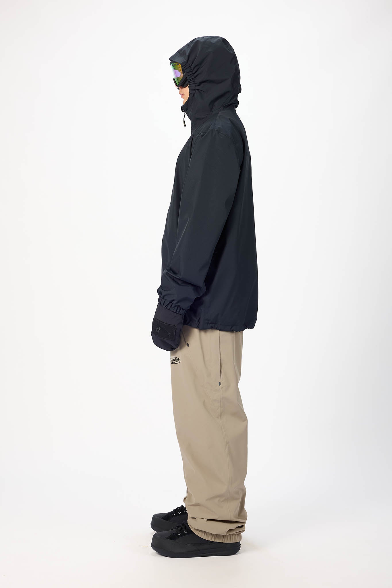 Person wearing a dark jacket and beige pants on a white background