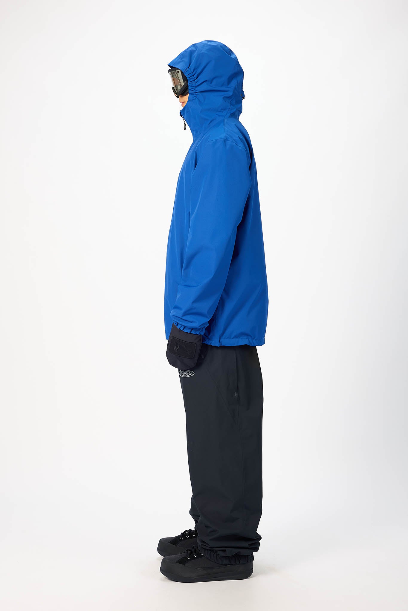 Person wearing a blue jacket and black pants on a white background