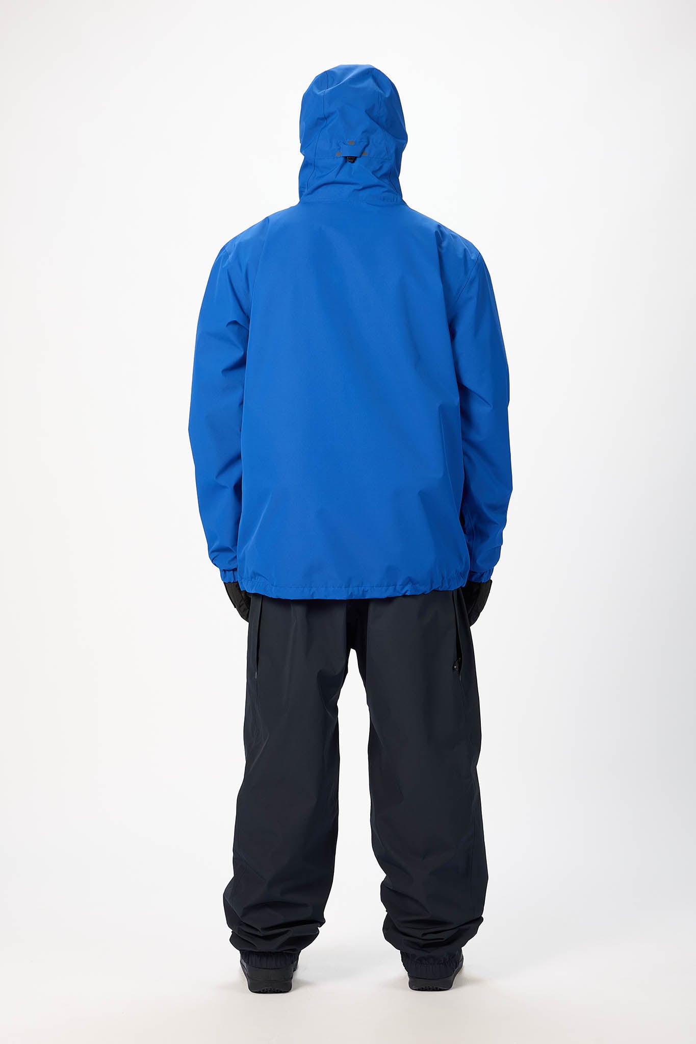 Person wearing a blue raincoat and black pants on a white background
