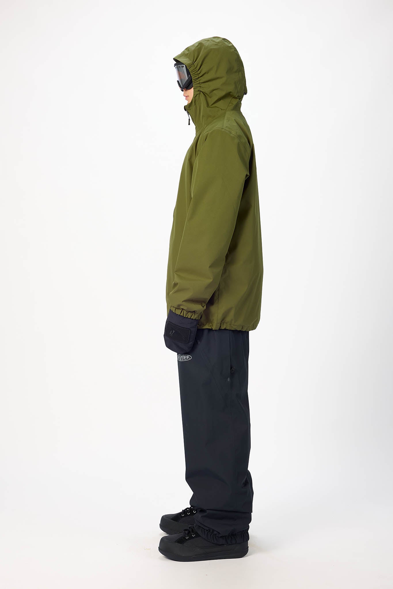 Person wearing a green jacket and black pants on a white background