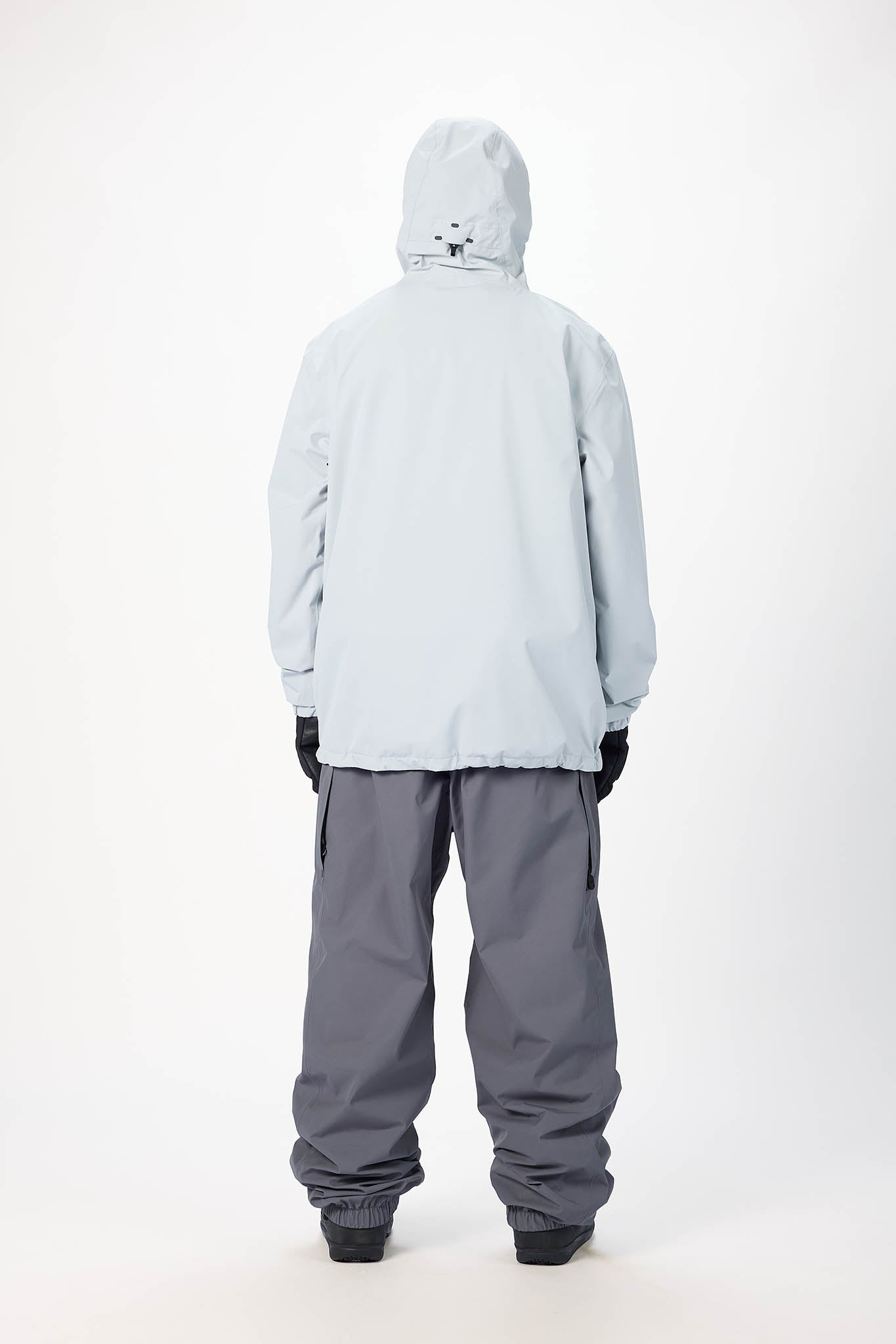 Person wearing a light gray jacket and gray pants on a white background