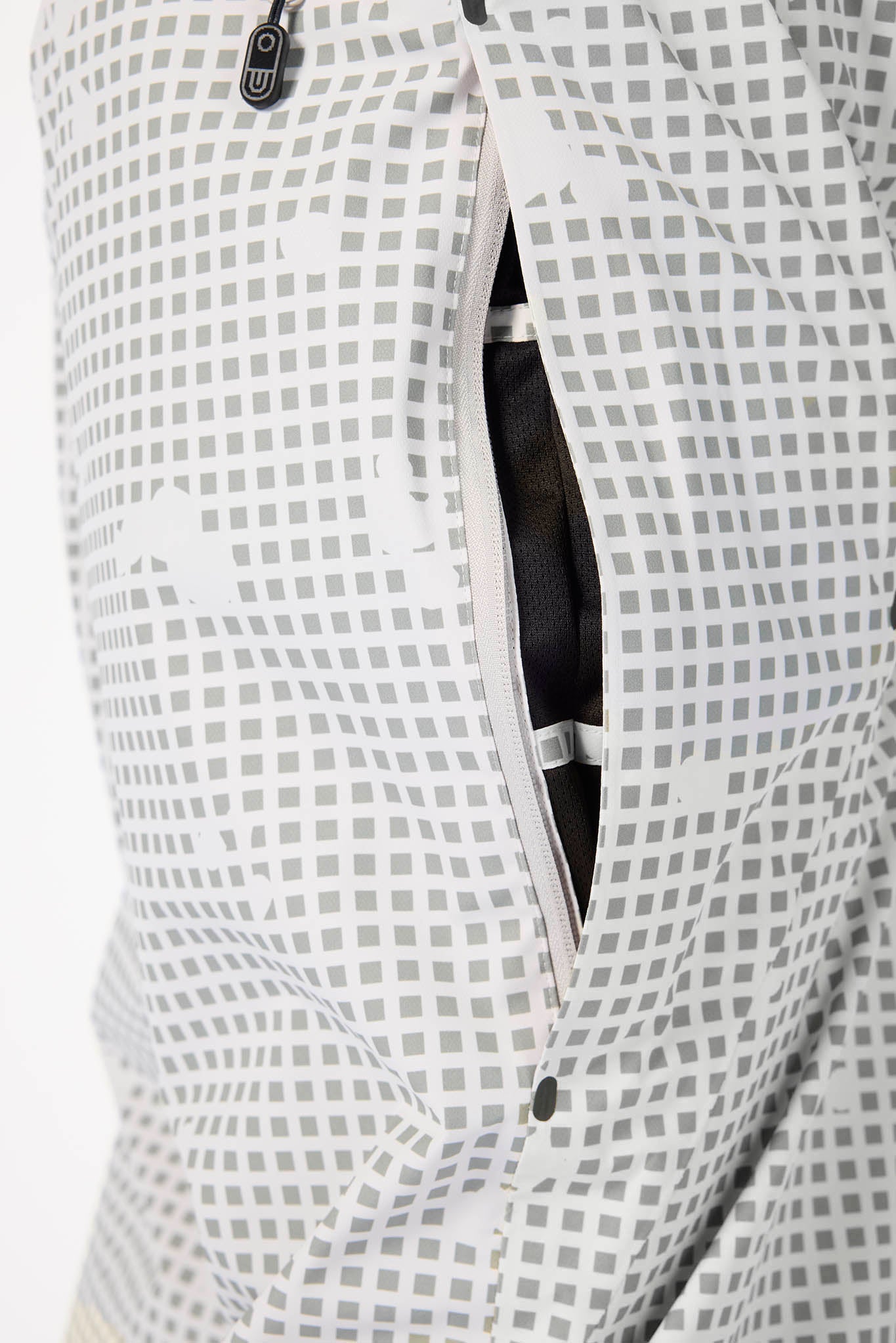 Close-up of a white and gray patterned garment with a partially unzipped pocket showing a black interior lining.