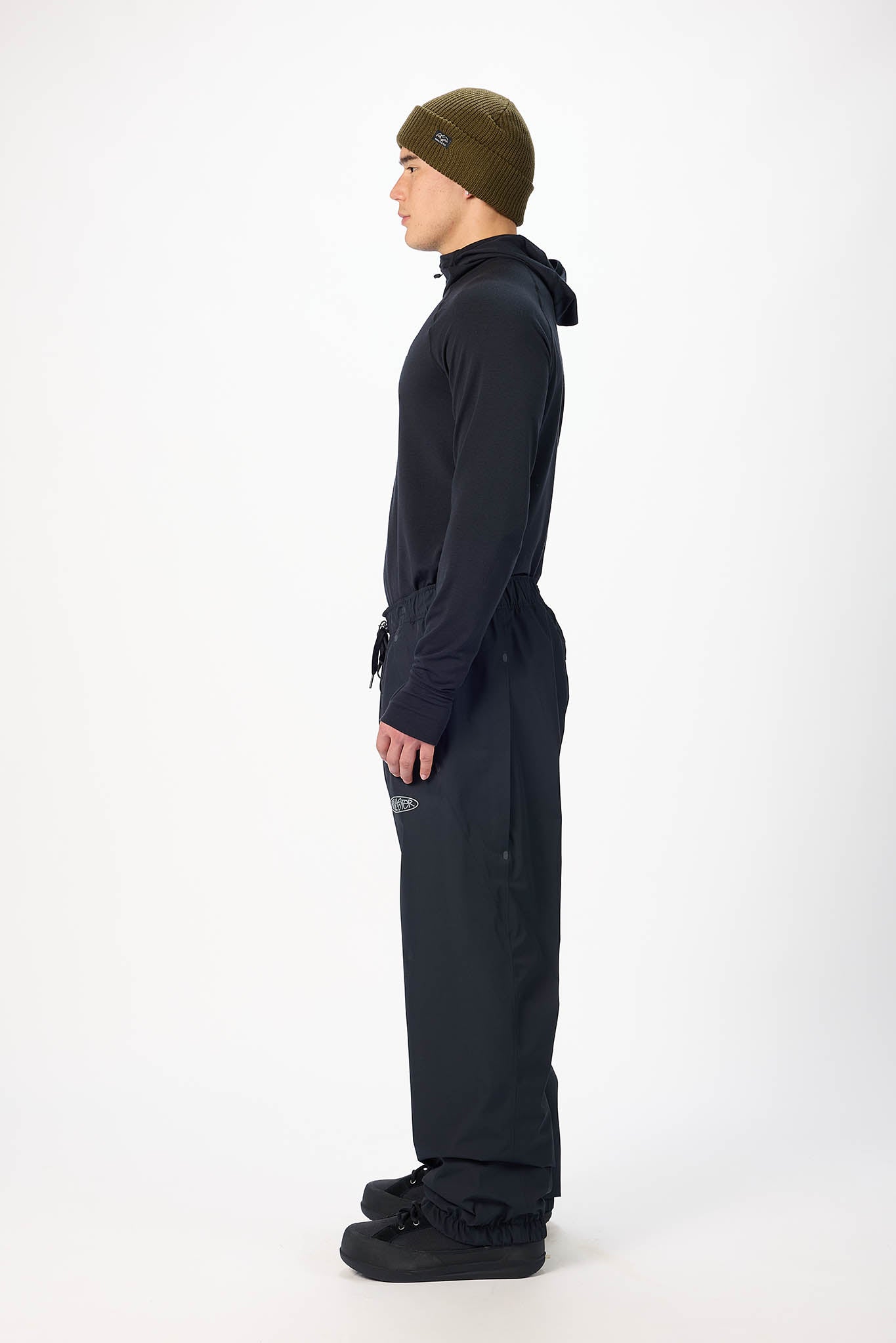 Person wearing a black snowsuit and green beanie on a white background