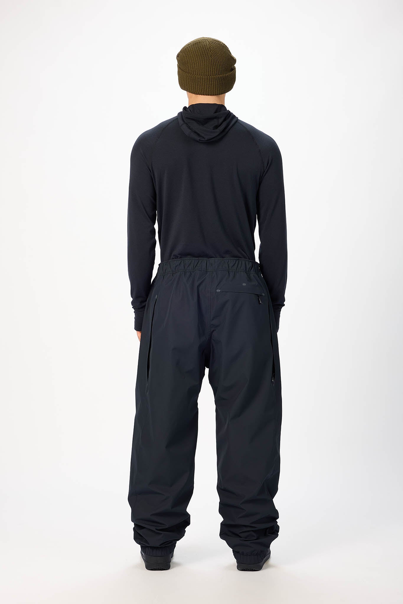 Person wearing a black jumpsuit and green beanie on a white background