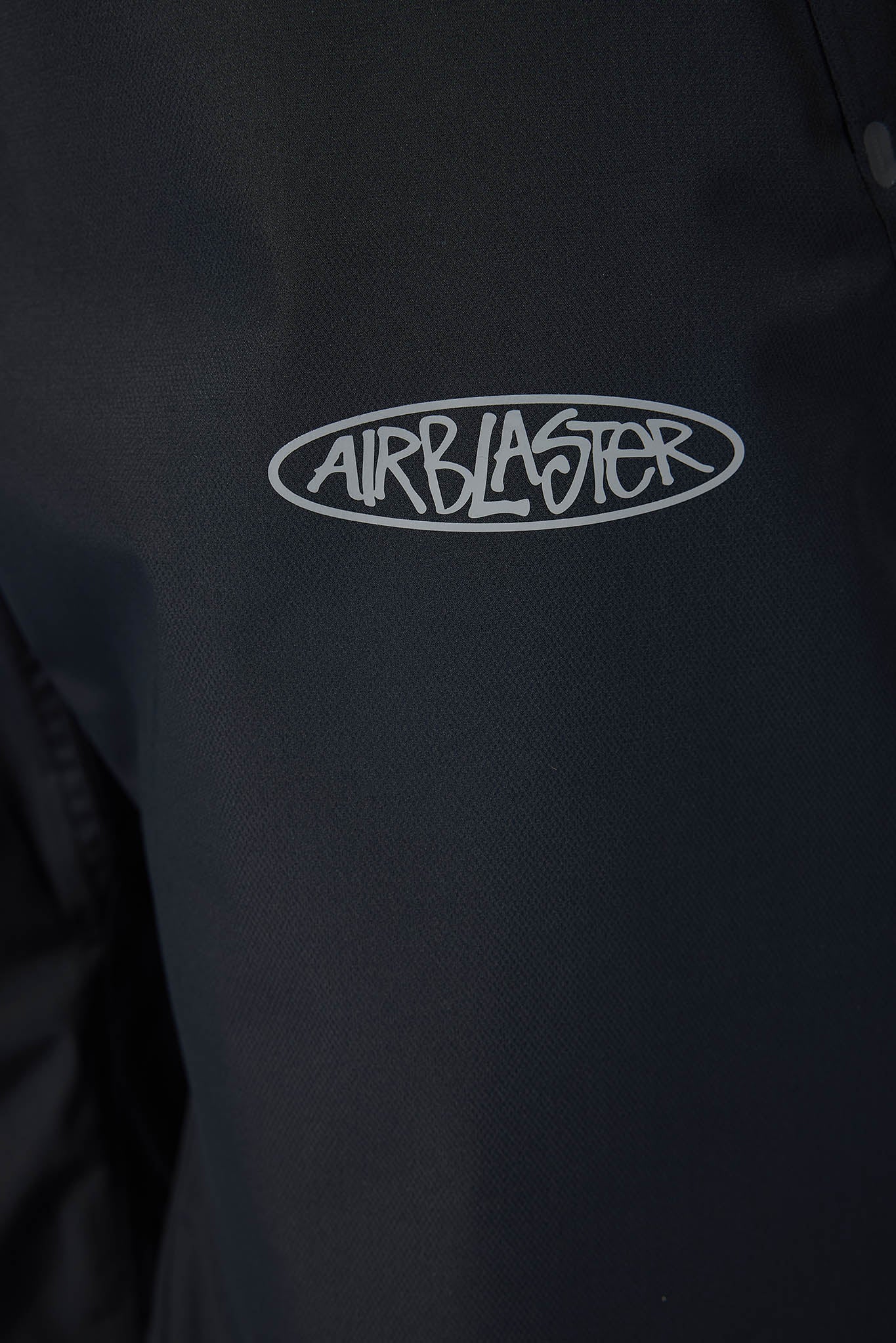 Close-up of a black jacket with 'Airblaster' logo on a dark background