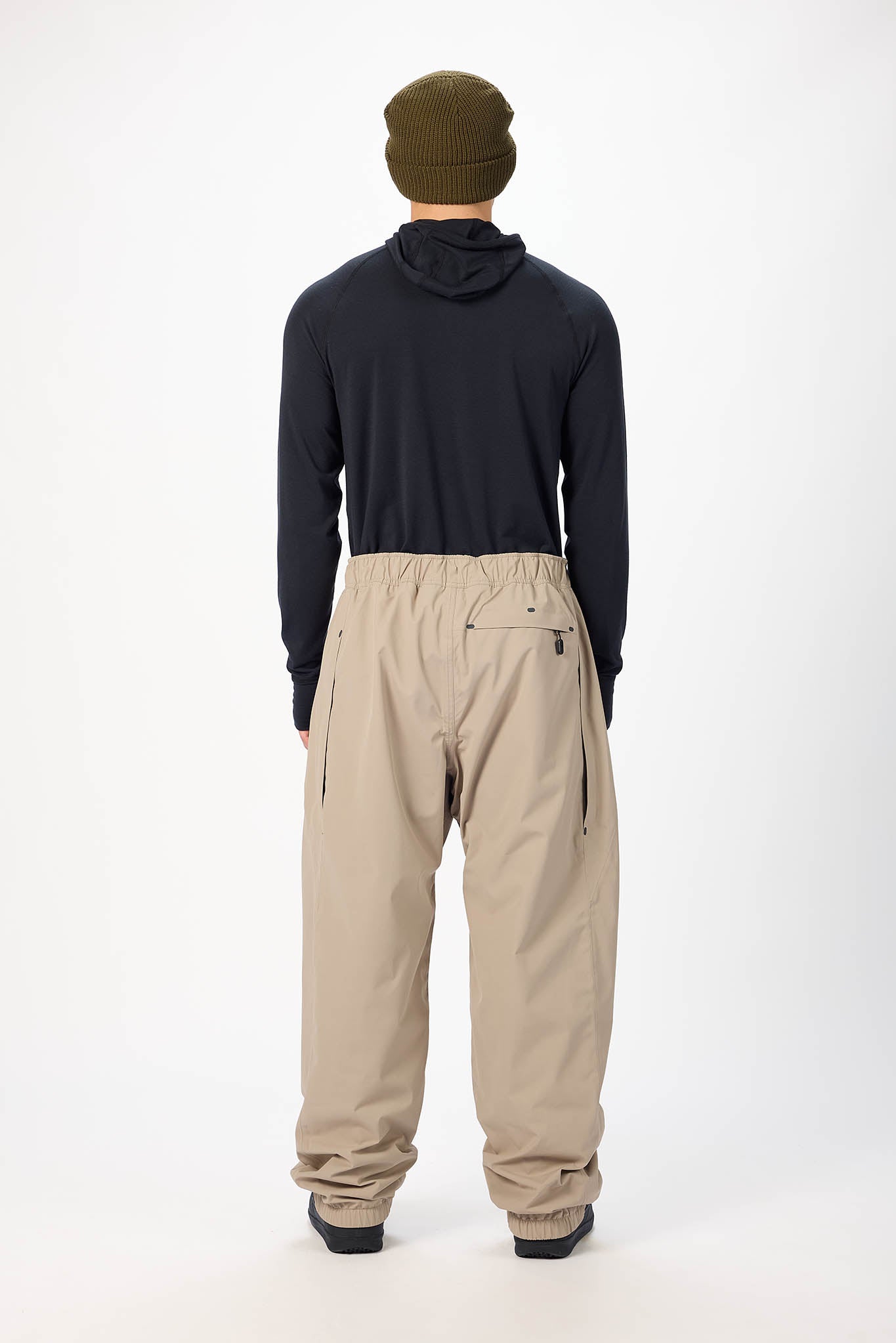 Person wearing a navy hoodie, beige pants, and a green beanie on a white background