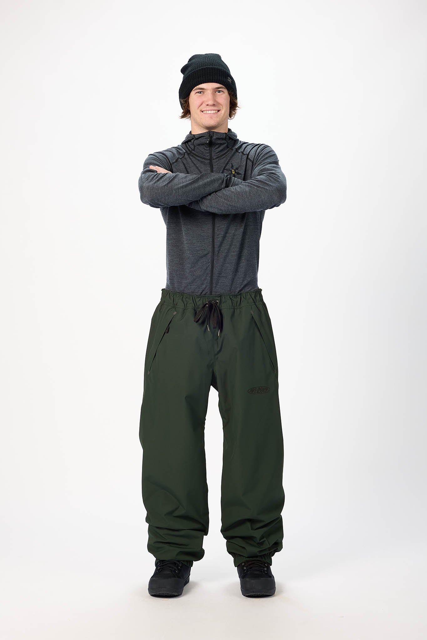 Person wearing a gray jacket and green pants on a white background