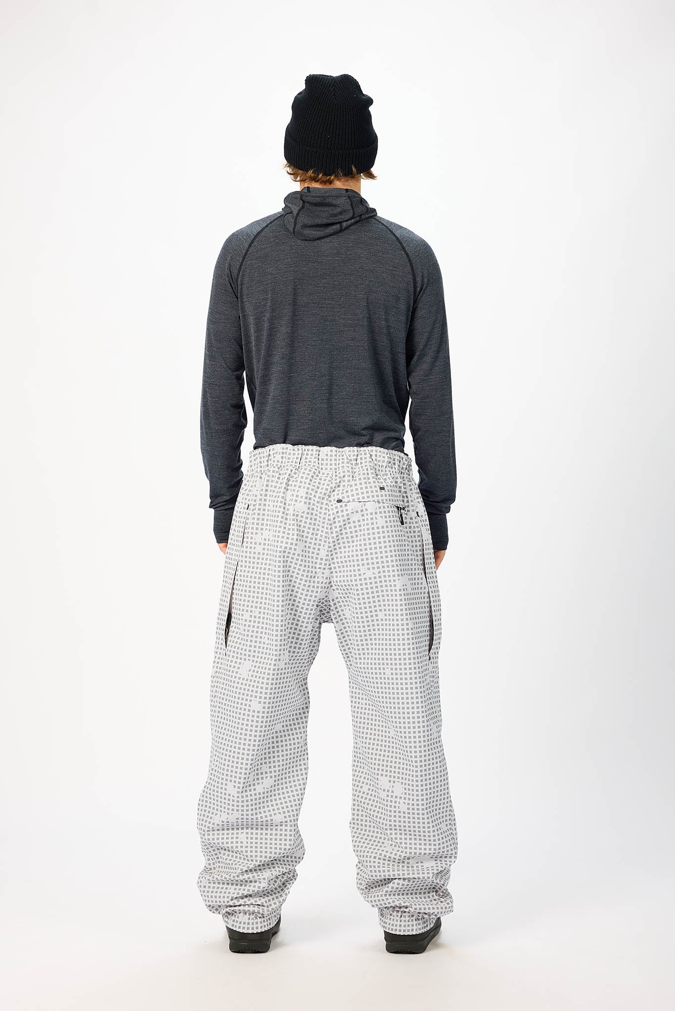 Person wearing a dark gray hoodie and checkered pants on a white background