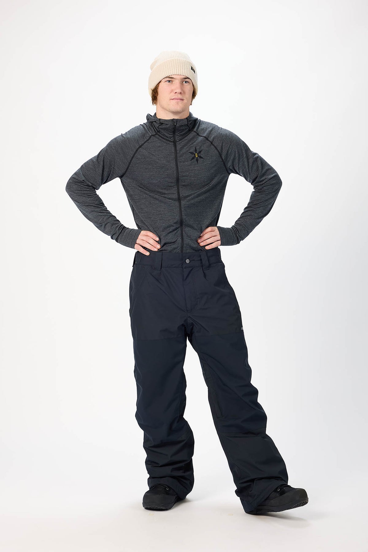 A man modeling a dark gray long-sleeve athletic jacket and dark navy snow pants against a plain white studio background.