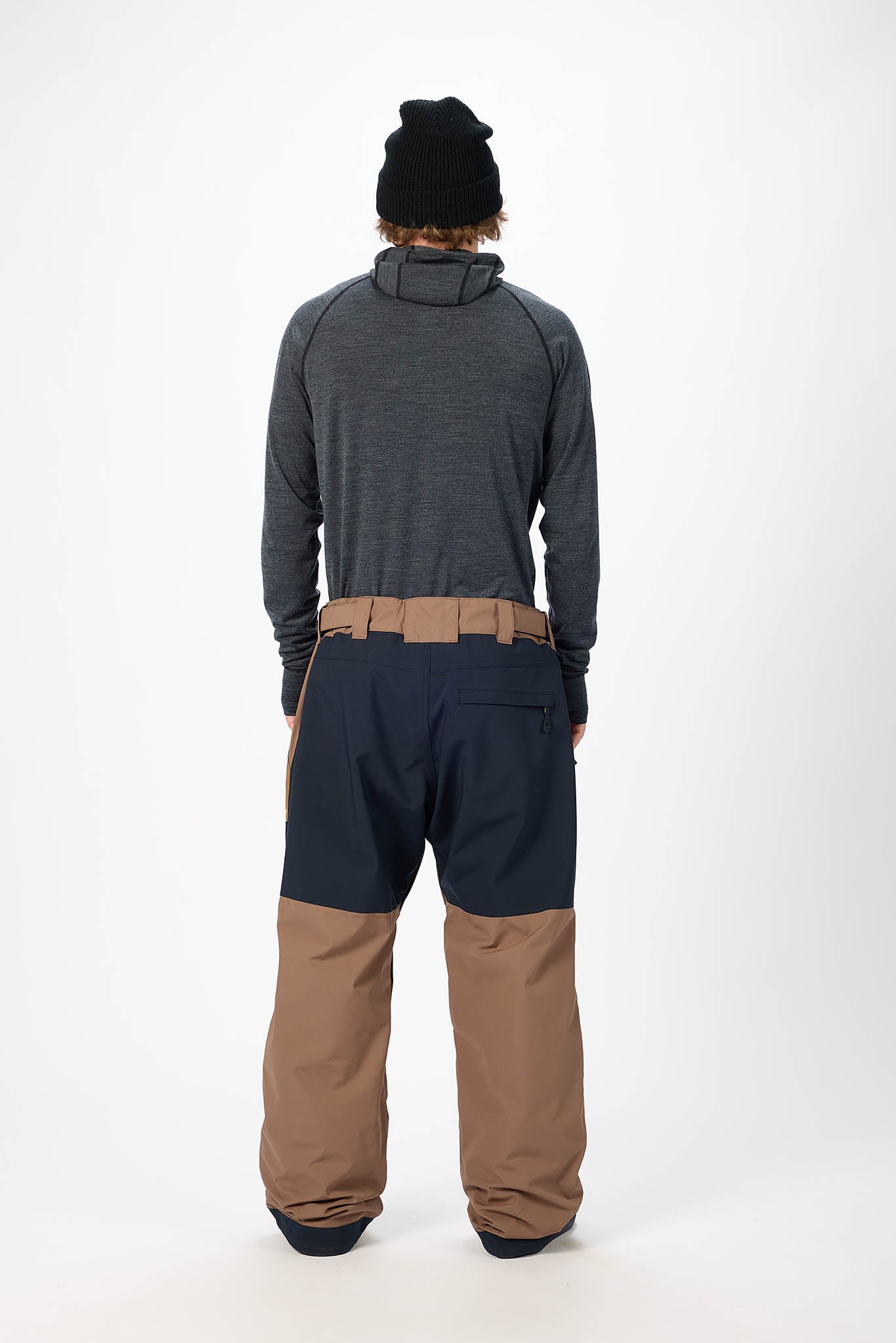 Person wearing a gray jacket and brown pants on a white background