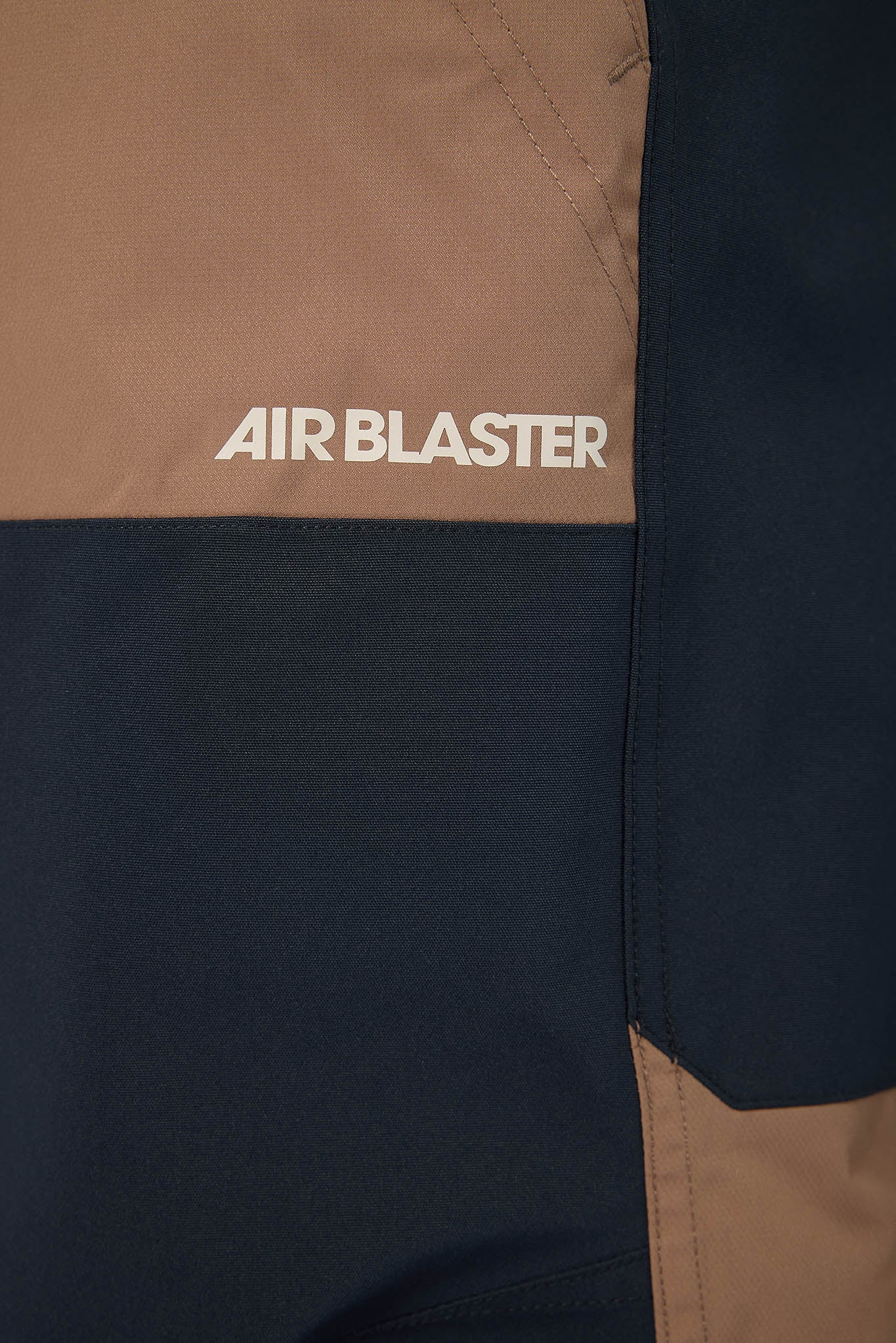 Close-up of a jacket with 'AIR BLASTER' branding on a brown and black background