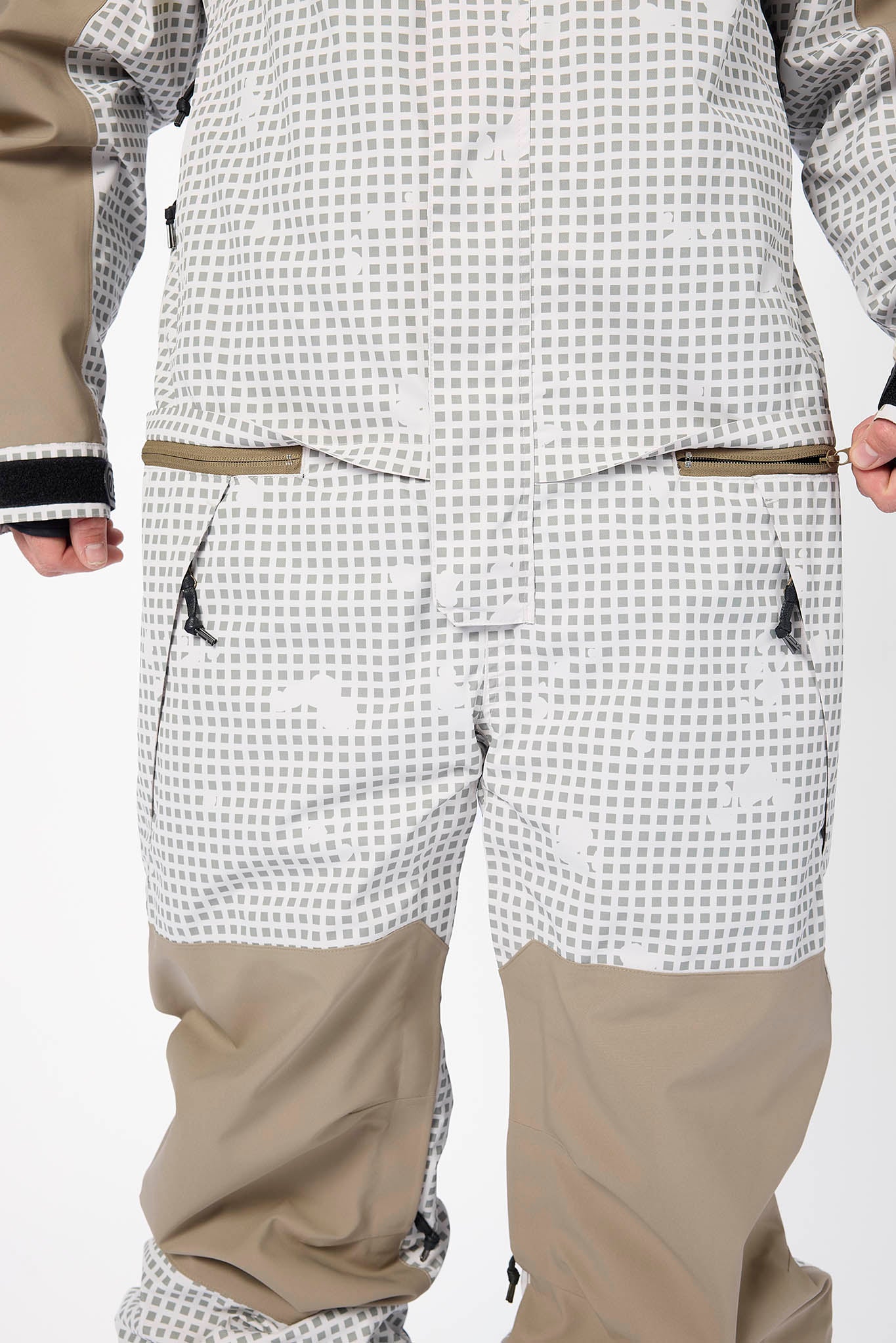 Person wearing a checkered snowsuit with beige pants on a white background