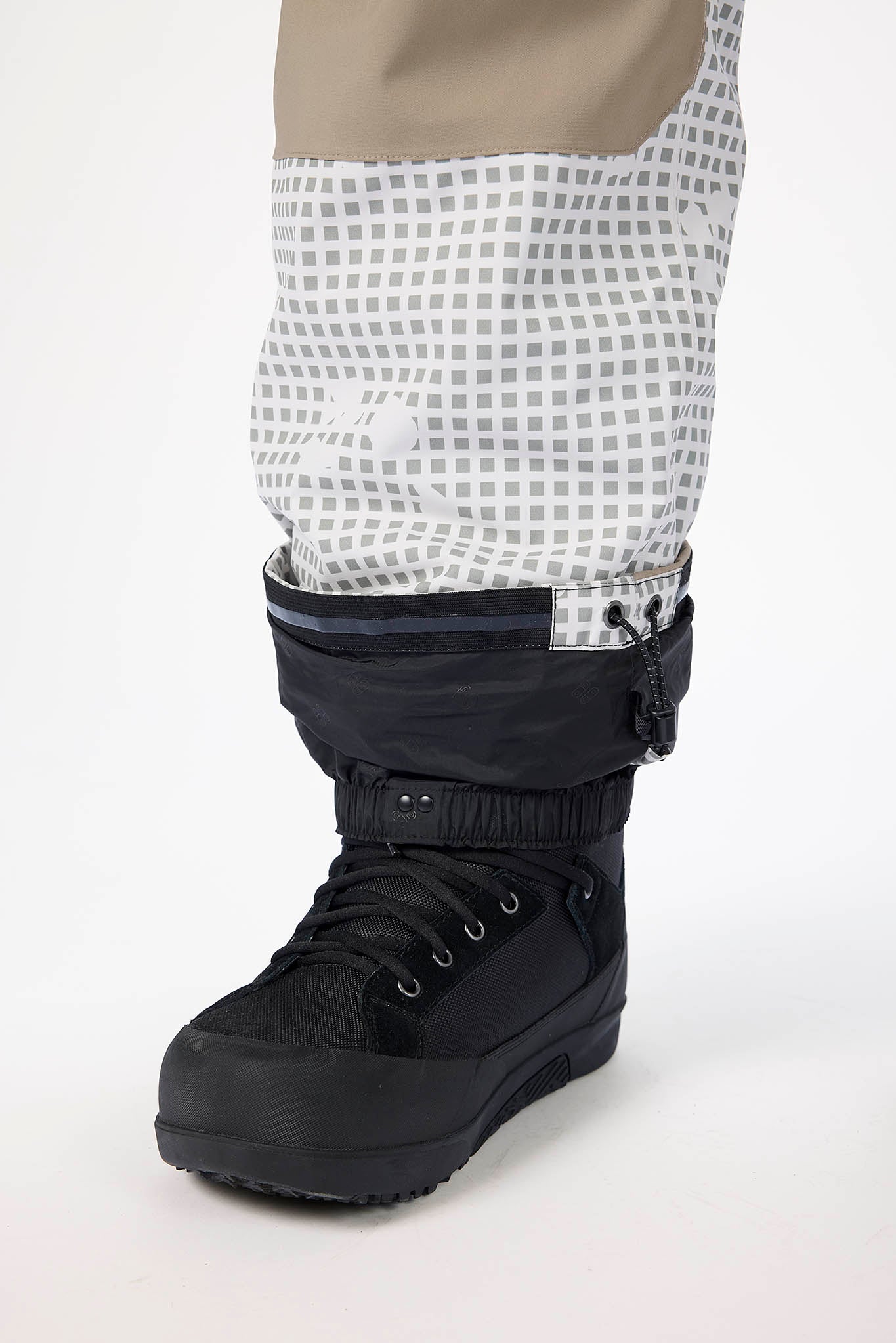 Black winter boot with a white checkered patterned legging on a white background