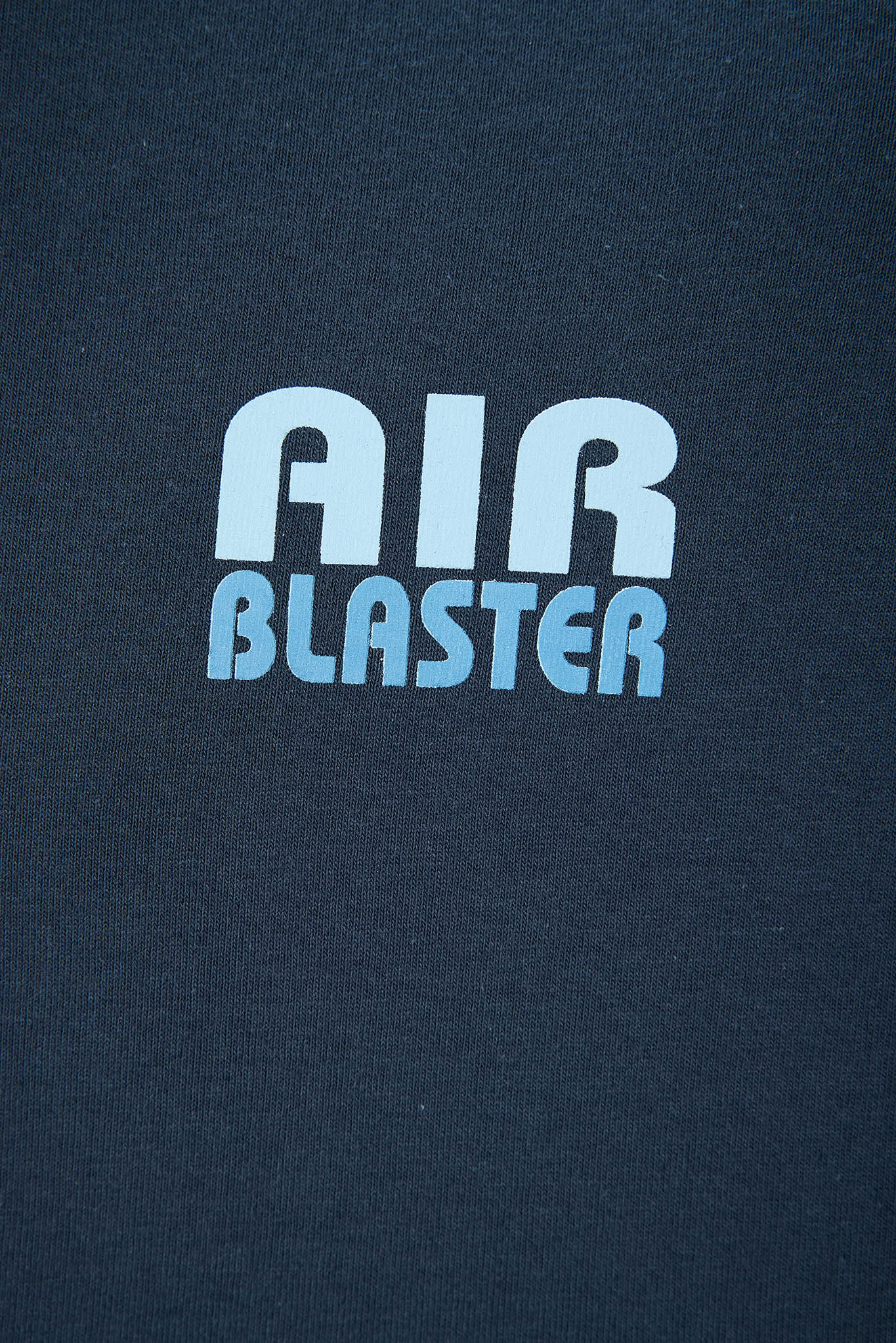 Close-up of a dark navy blue fabric surface with a light blue and white 'AIR BLASTER' logo printed on the front.