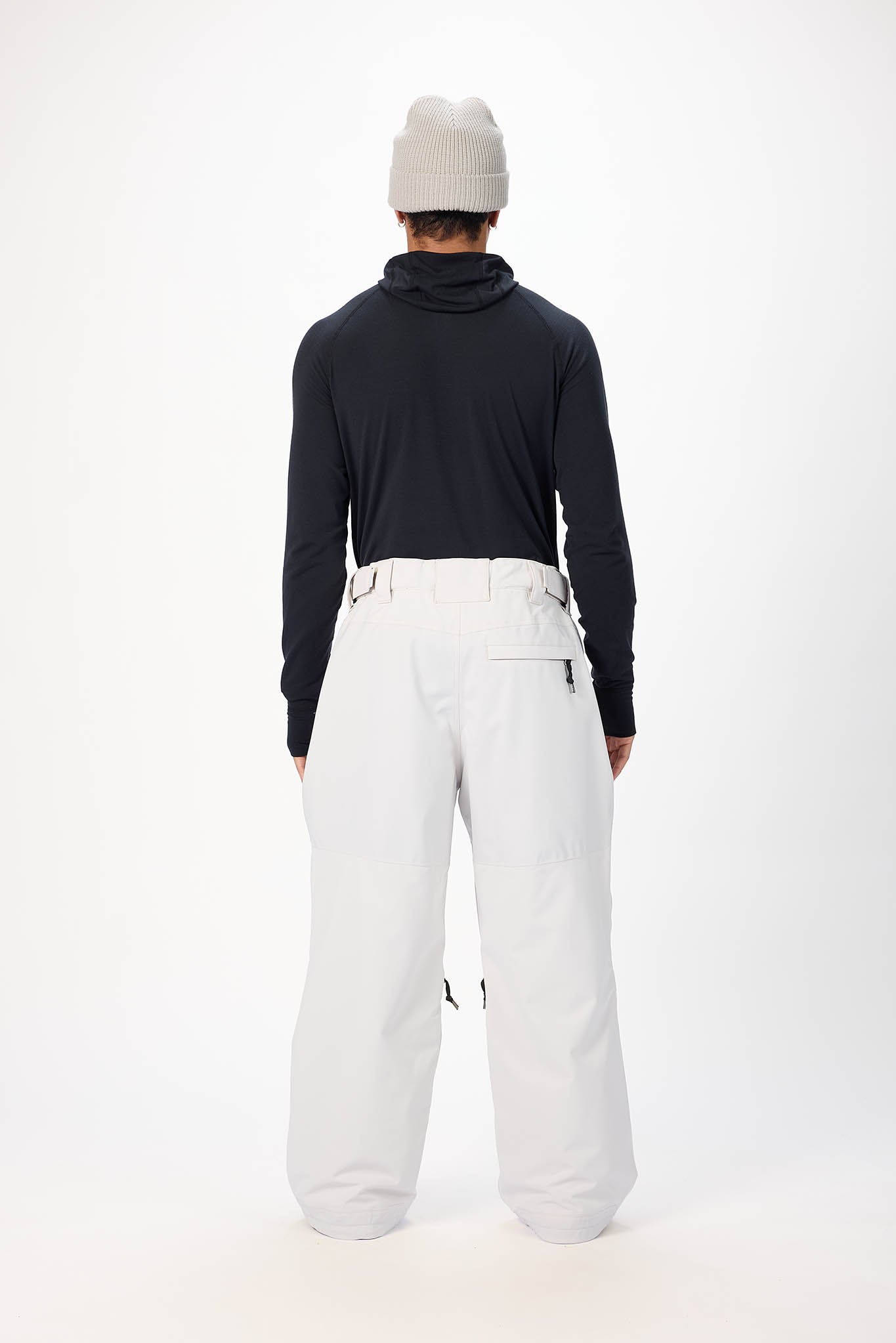 Person wearing a black long-sleeve top and white pants on a white background