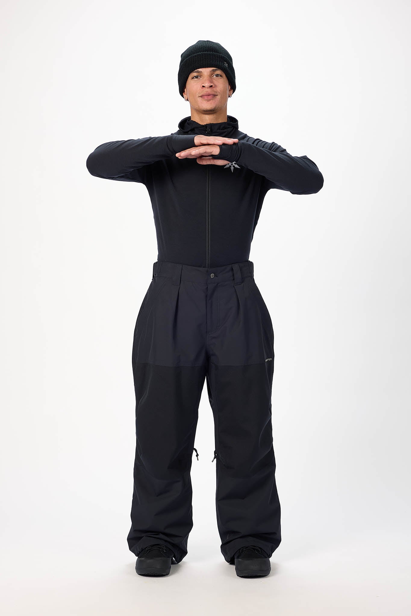 Person wearing a black snowsuit and hat on a white background