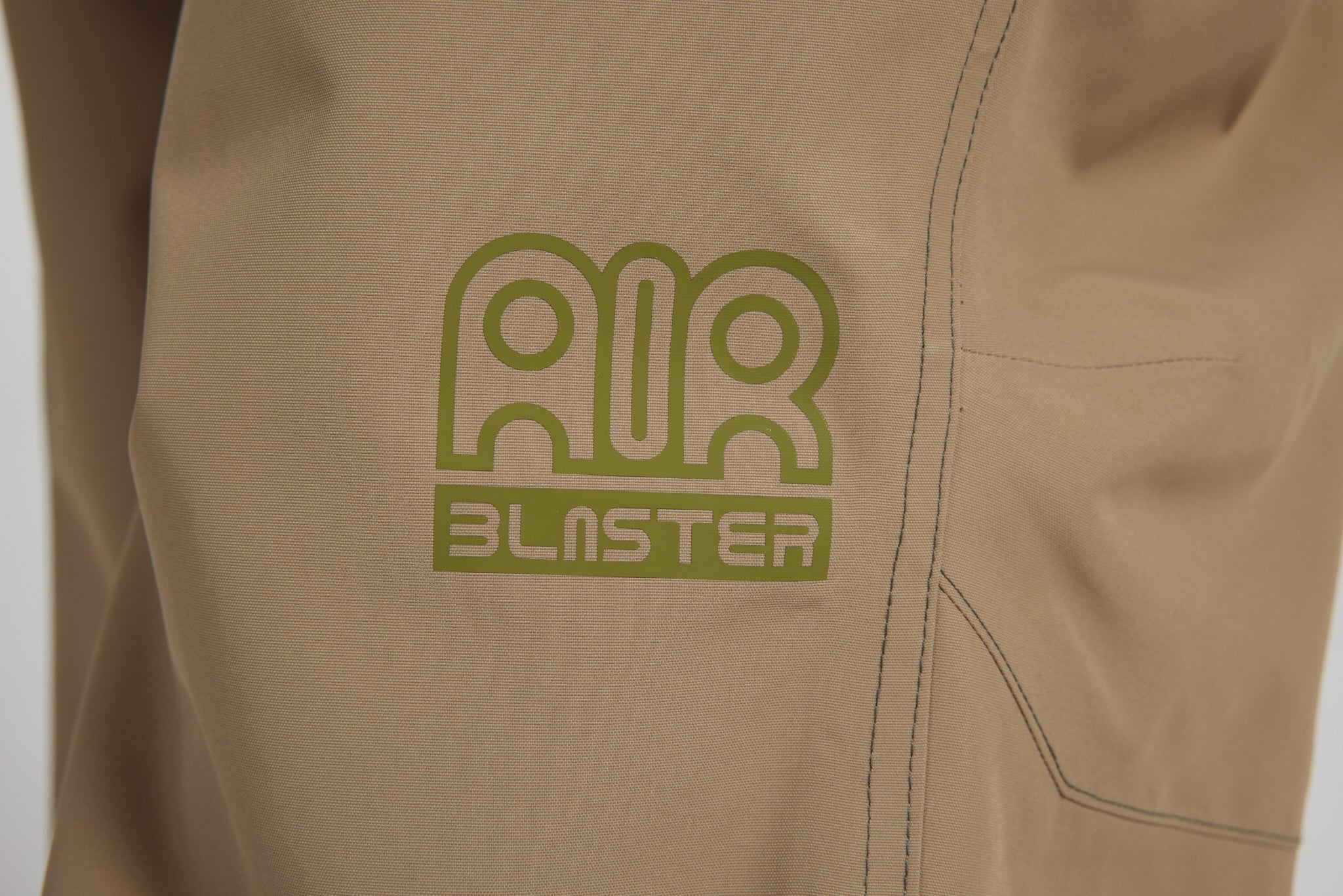 Close-up of a tan or khaki garment with a green outlined 'AIR BLASTER' logo printed on the chest.