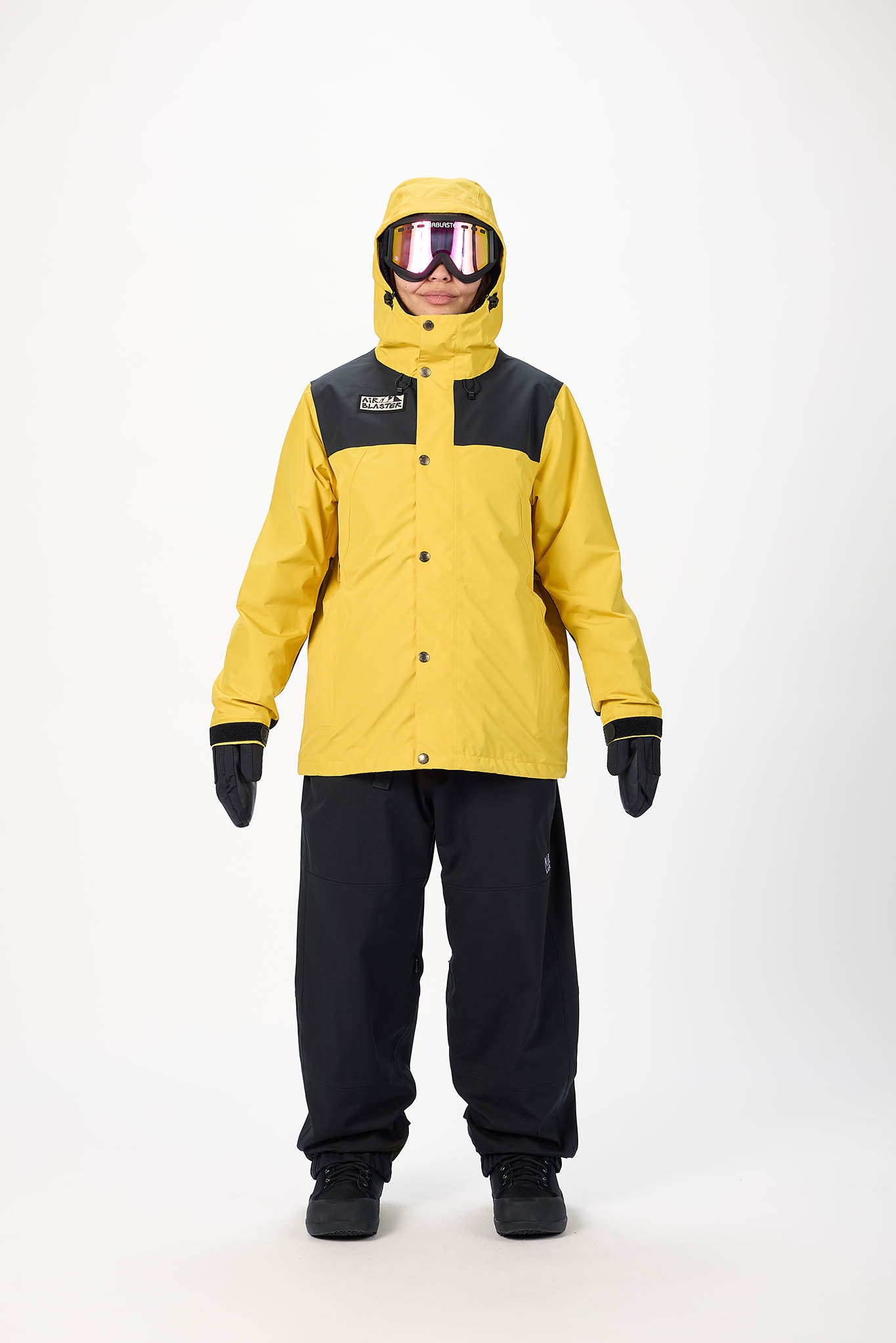 Person wearing a yellow and black snowsuit with goggles on a white background