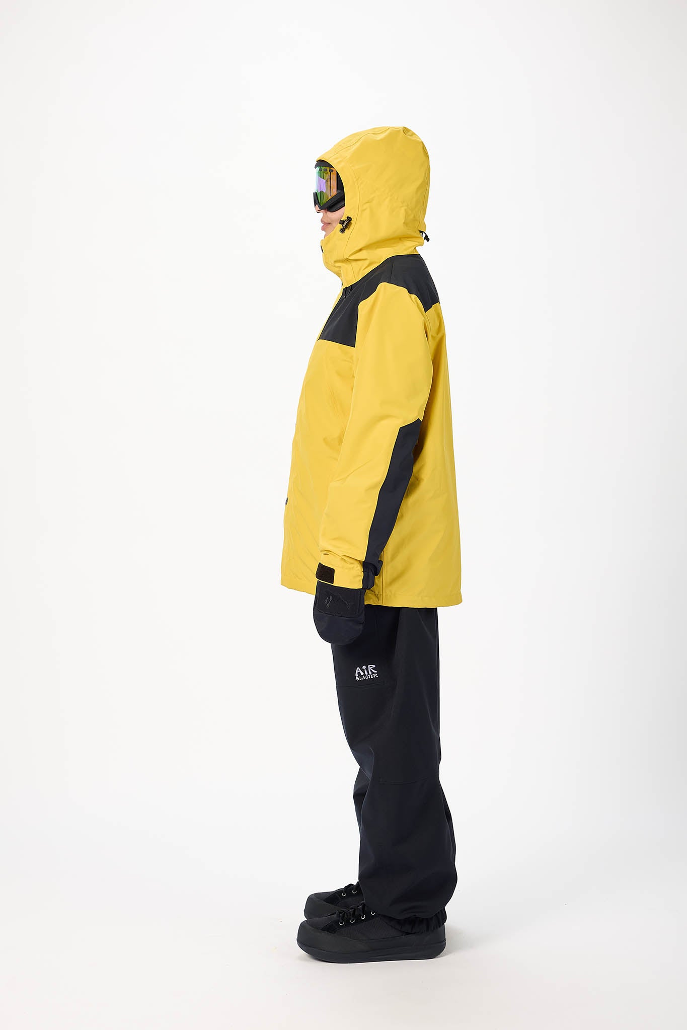 Person wearing a yellow and black snow jacket with matching pants on a white background