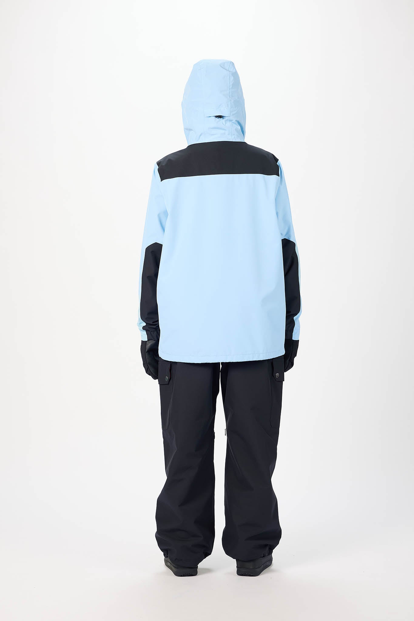 Person wearing a light blue and black snow jacket with matching pants on a white background