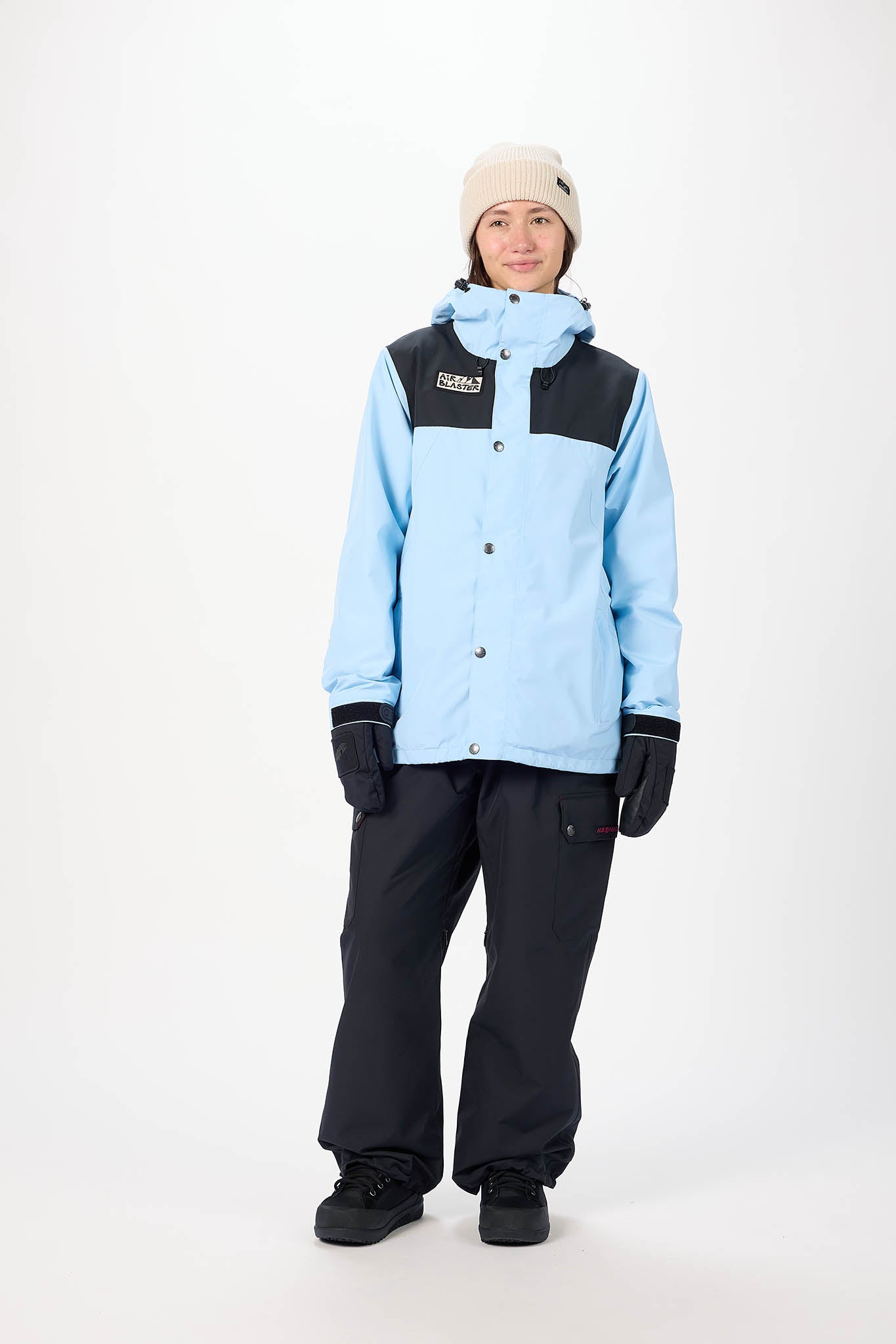Person wearing a light blue and black snow jacket with matching pants on a white background