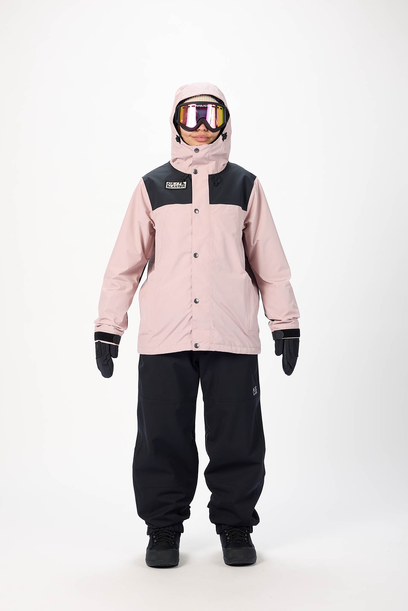 Person wearing a pink and black snowsuit with goggles on a white background