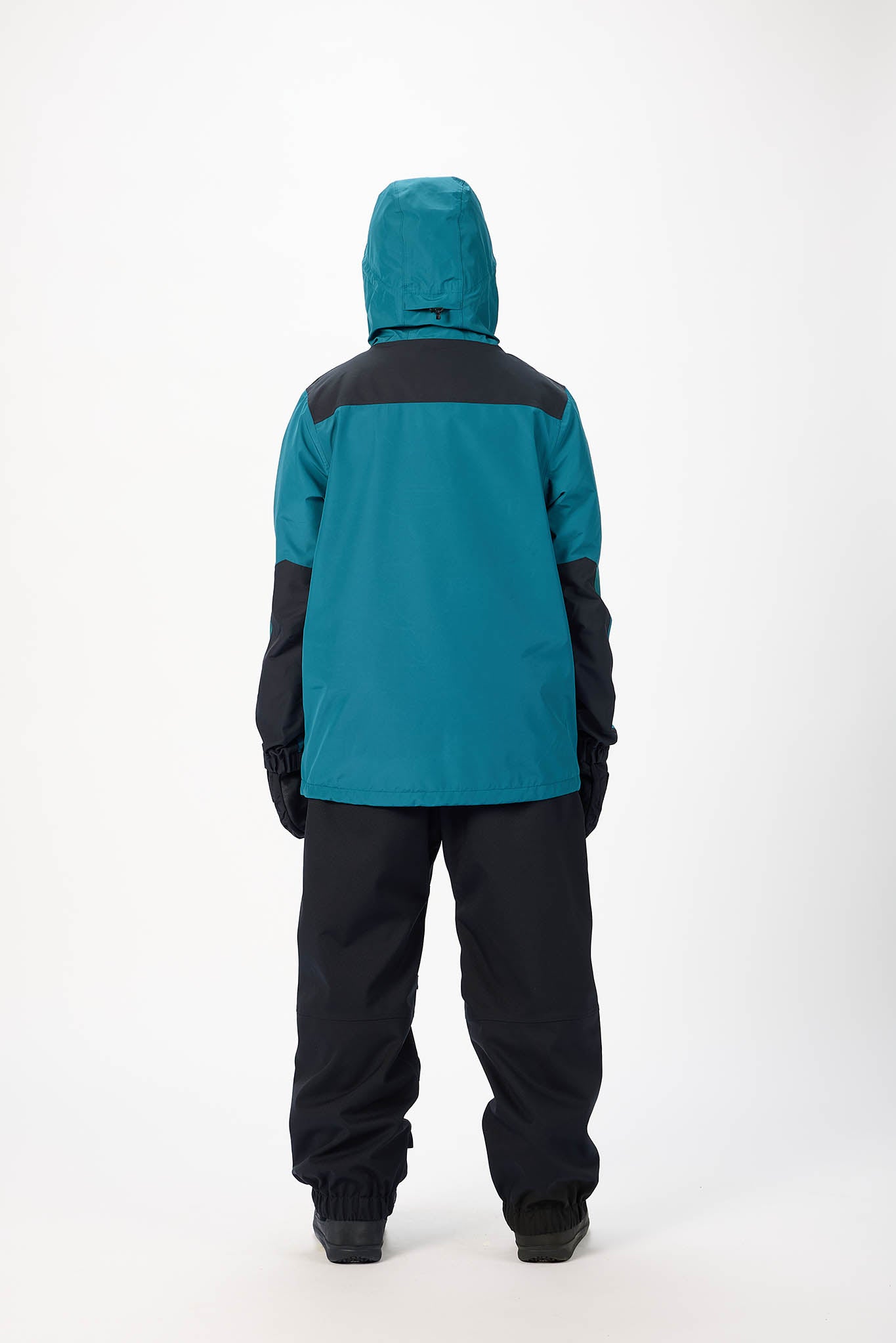 Person wearing a teal and black snowsuit on a white background