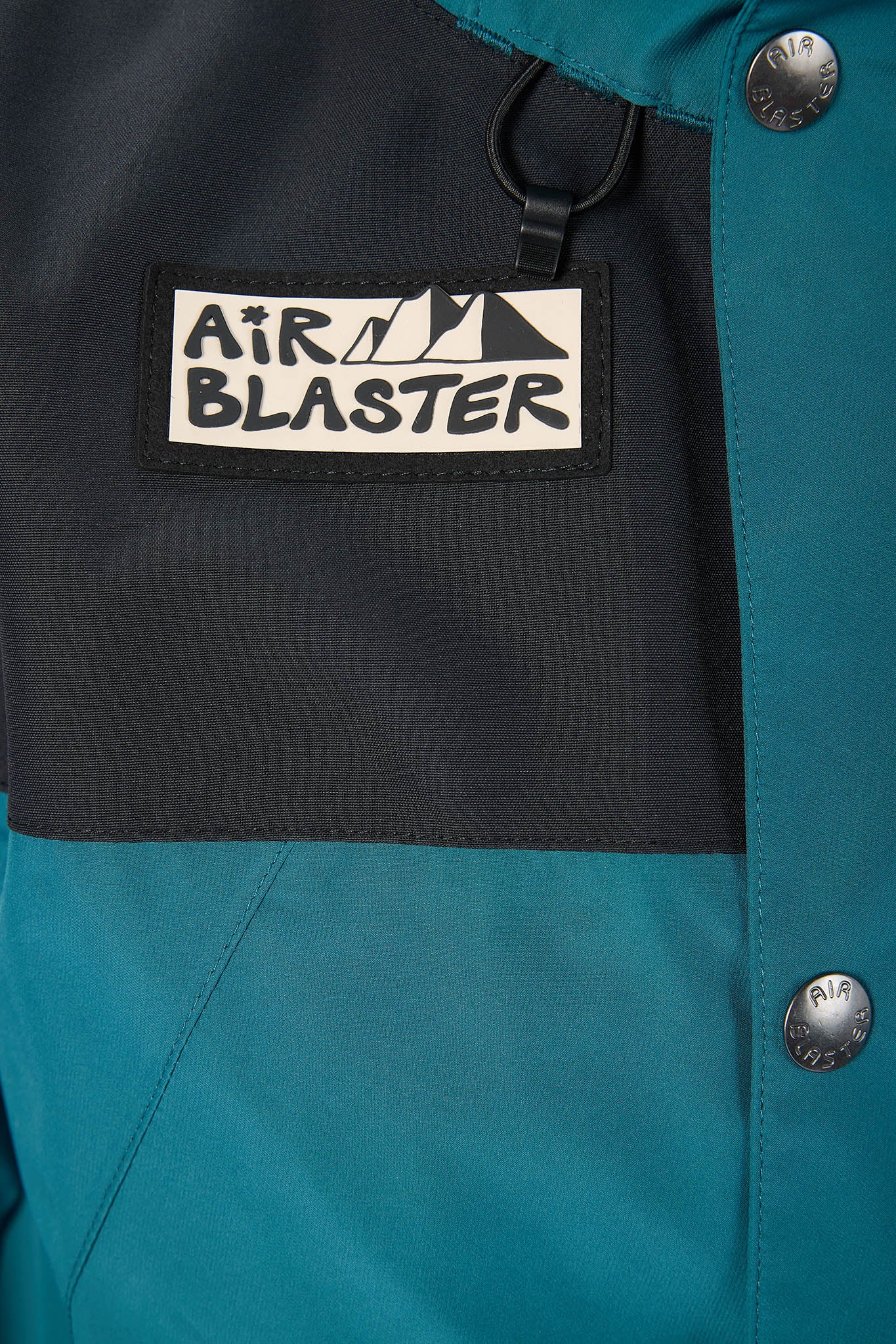 Close-up of a teal jacket with an 'Air Blaster' logo on a black patch.