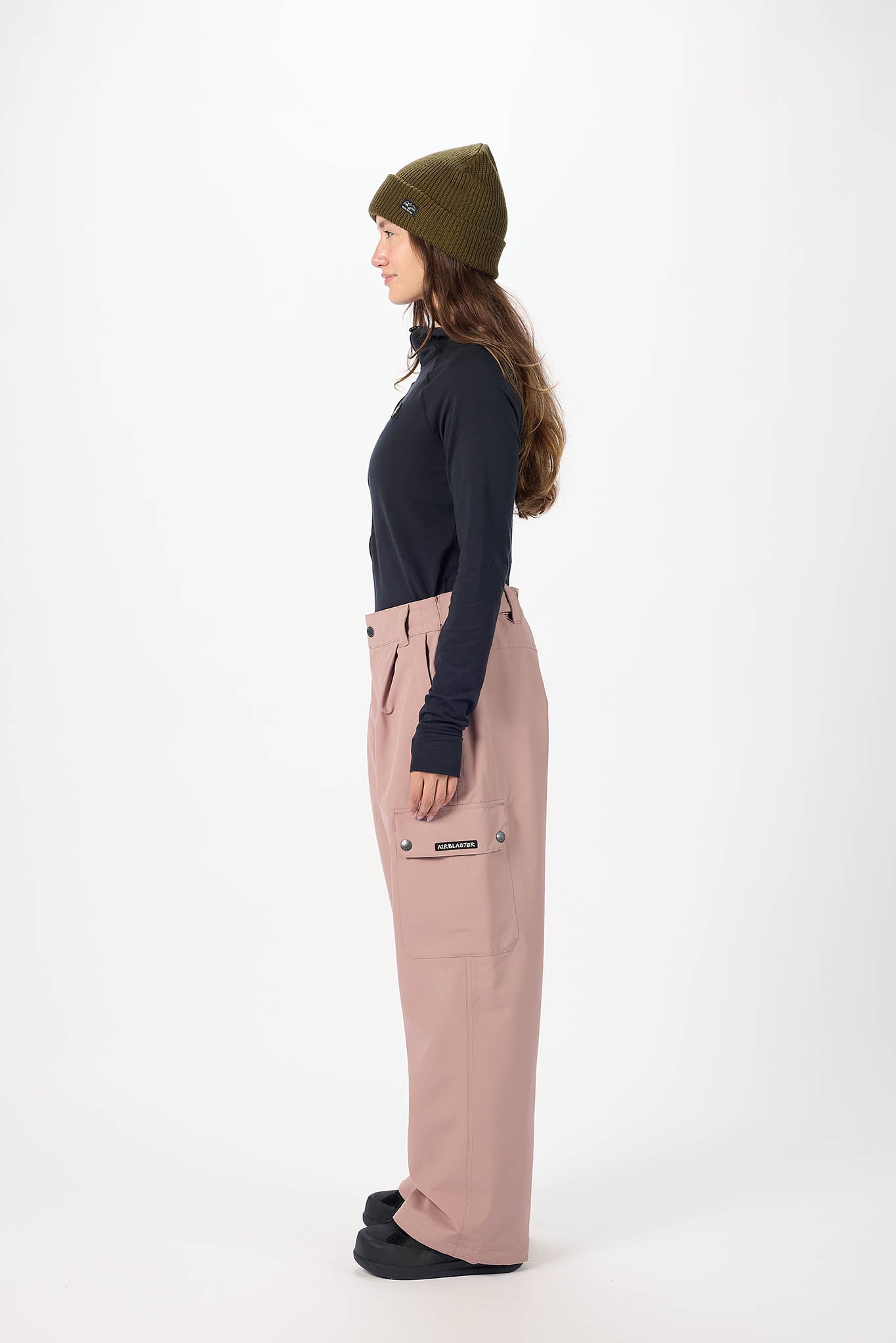 Person wearing a black top, beige pants, and a green beanie on a white background