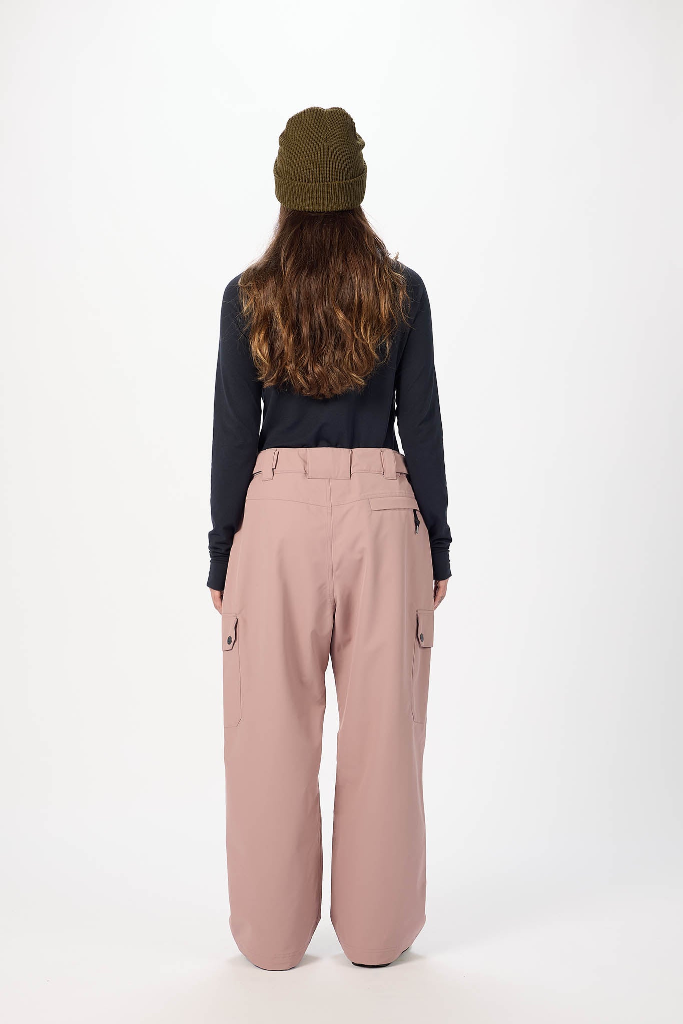 Person wearing a black top and pink pants with a green beanie on a white background